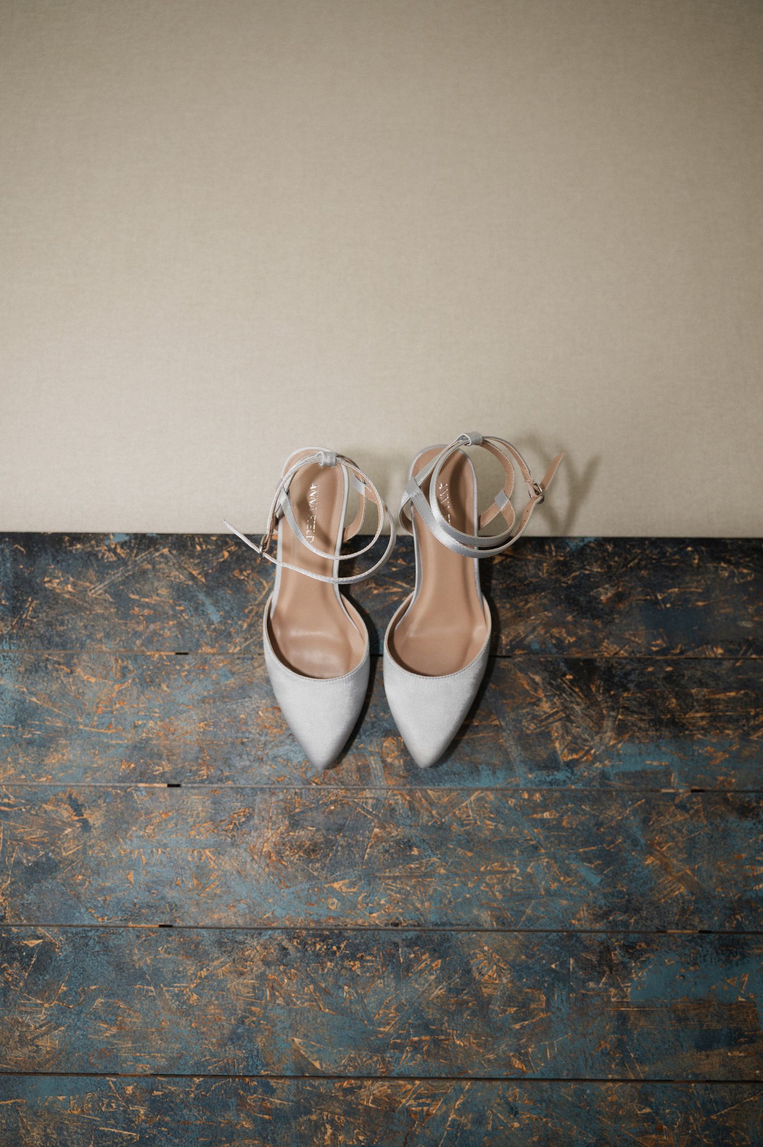 White bridal shoes placed on a rustic blue wooden floor.