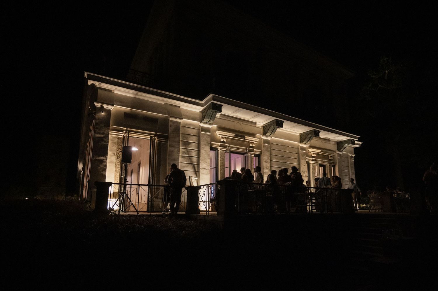 Elegant venue exterior illuminated at night with guests gathered outside under warm lights.