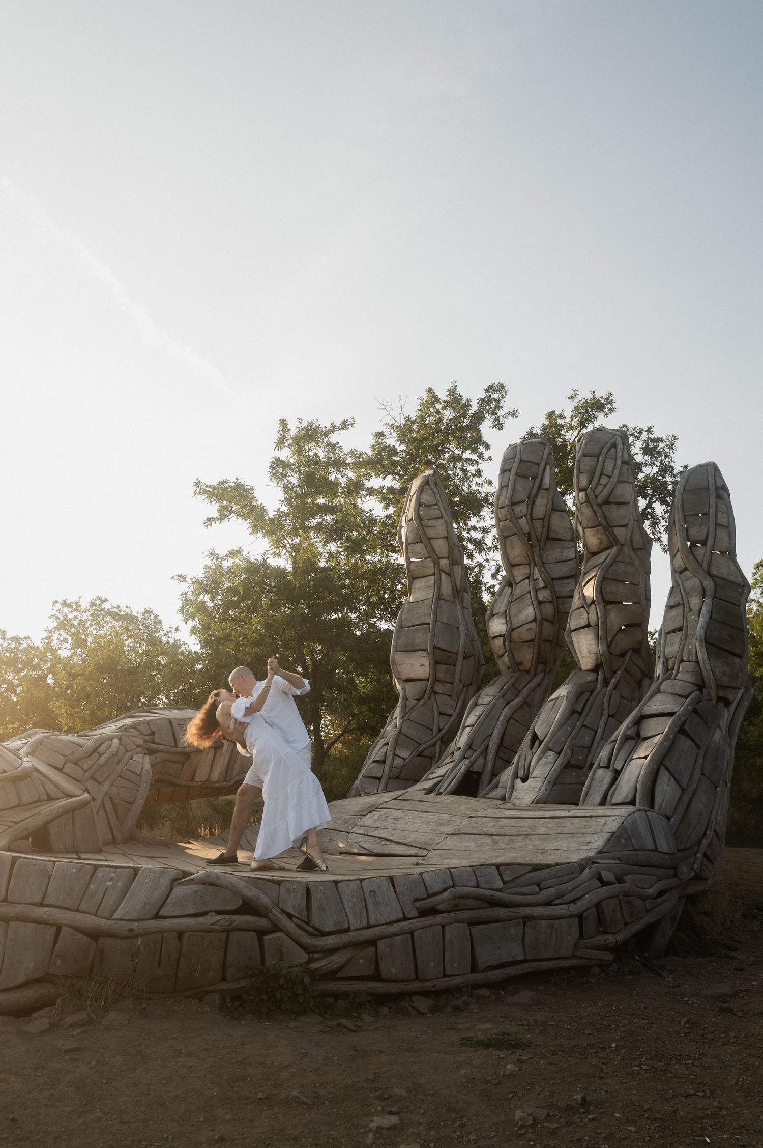 A series of four photos showing a couple posing at sunset on a large sculptural stone bench in a park setting.