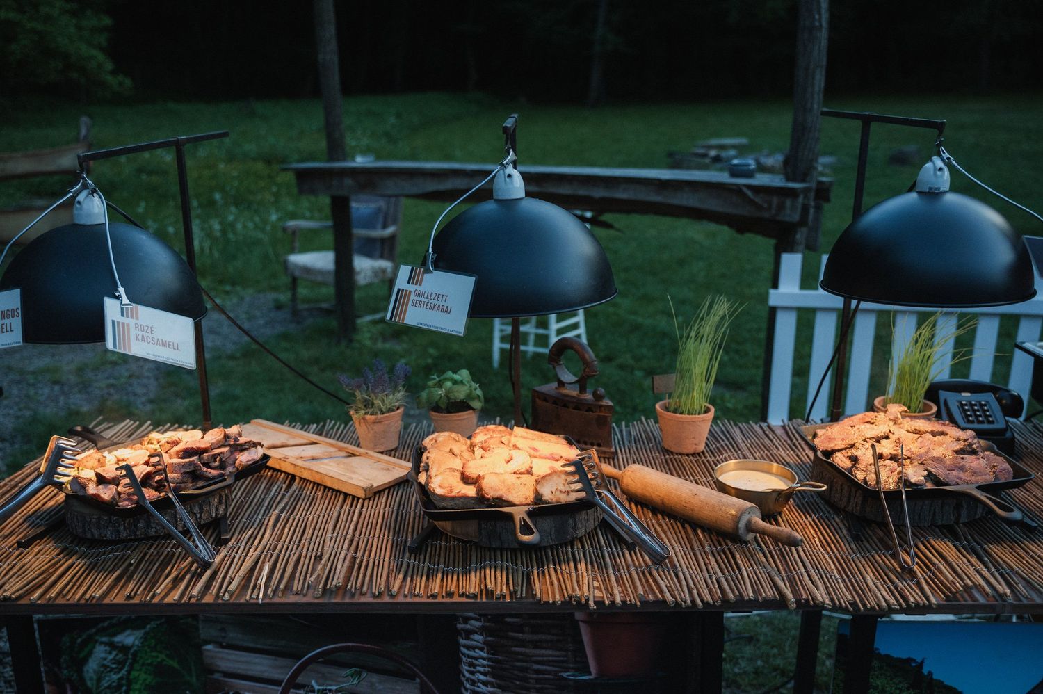 Grilled salmon fillets cooking on a wooden plank with herbs and citrus on an outdoor barbecue grill.