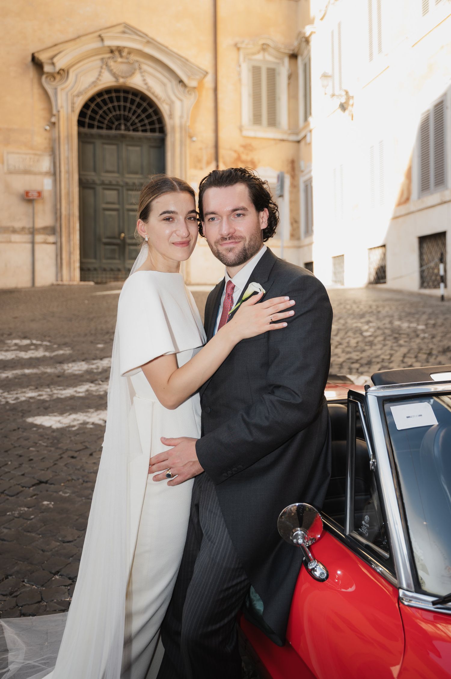 A romantic wedding portrait featuring a classic car and beautiful Italian architecture.