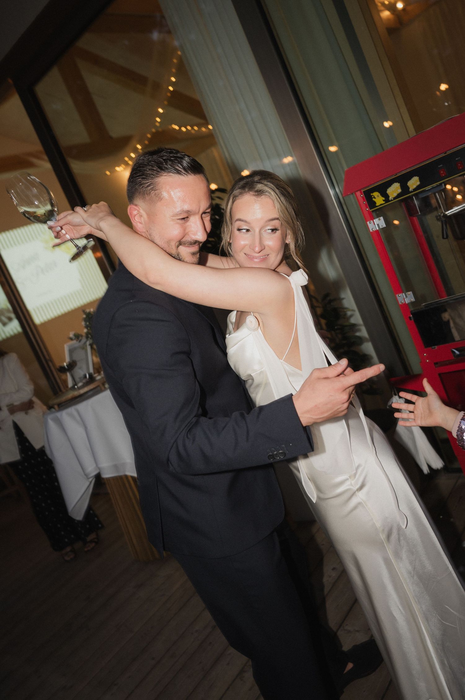 A couple shares a romantic first dance at their wedding reception, with the bride in a white gown and groom in a dark suit.