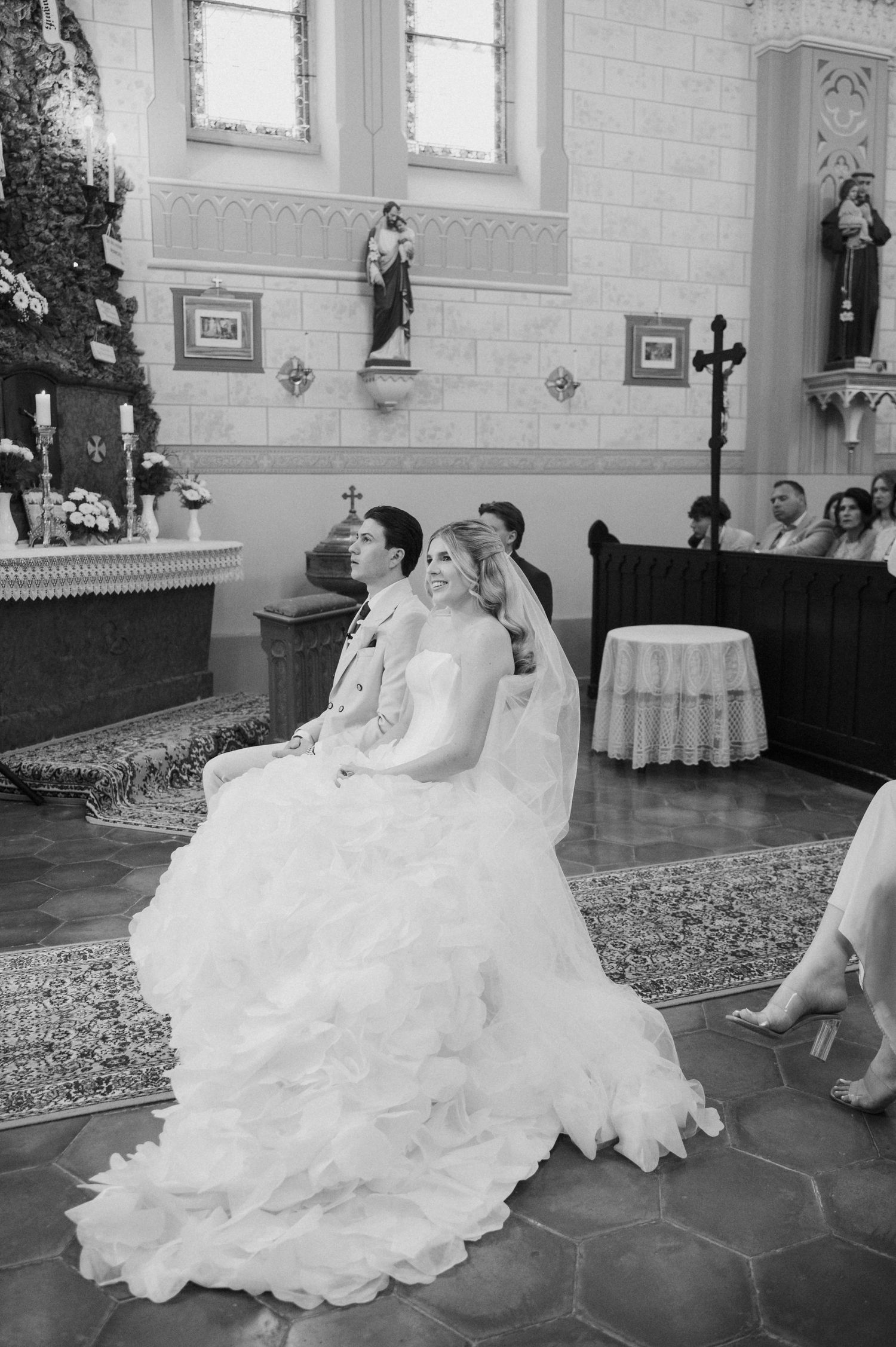 Black and white photo of bride and groom seated together during a church wedding ceremony.