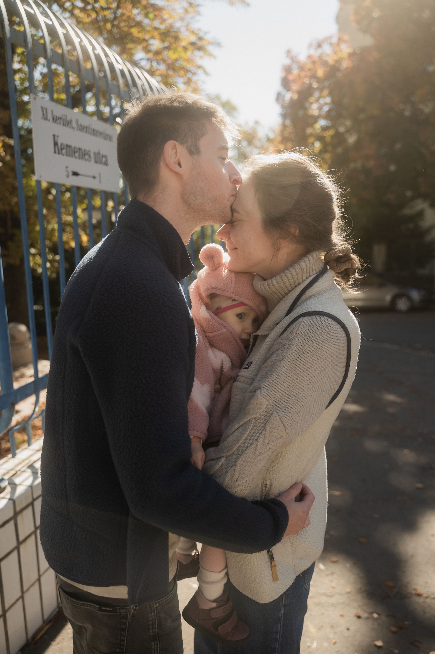 A tender family moment shared outdoors on an autumn day near a gate.