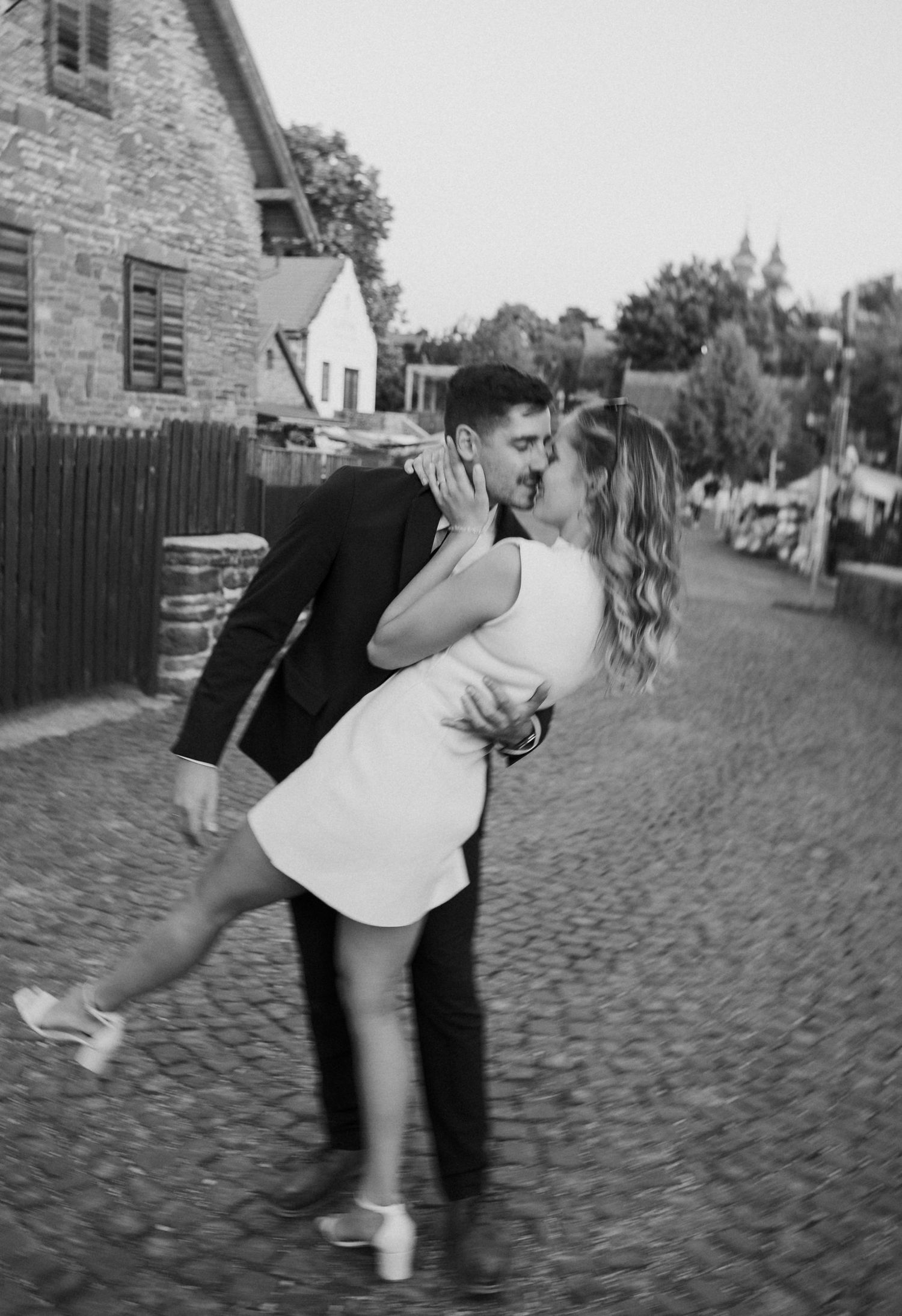 A sequence of black and white photos showing two people dancing and spinning together on a cobblestone street.