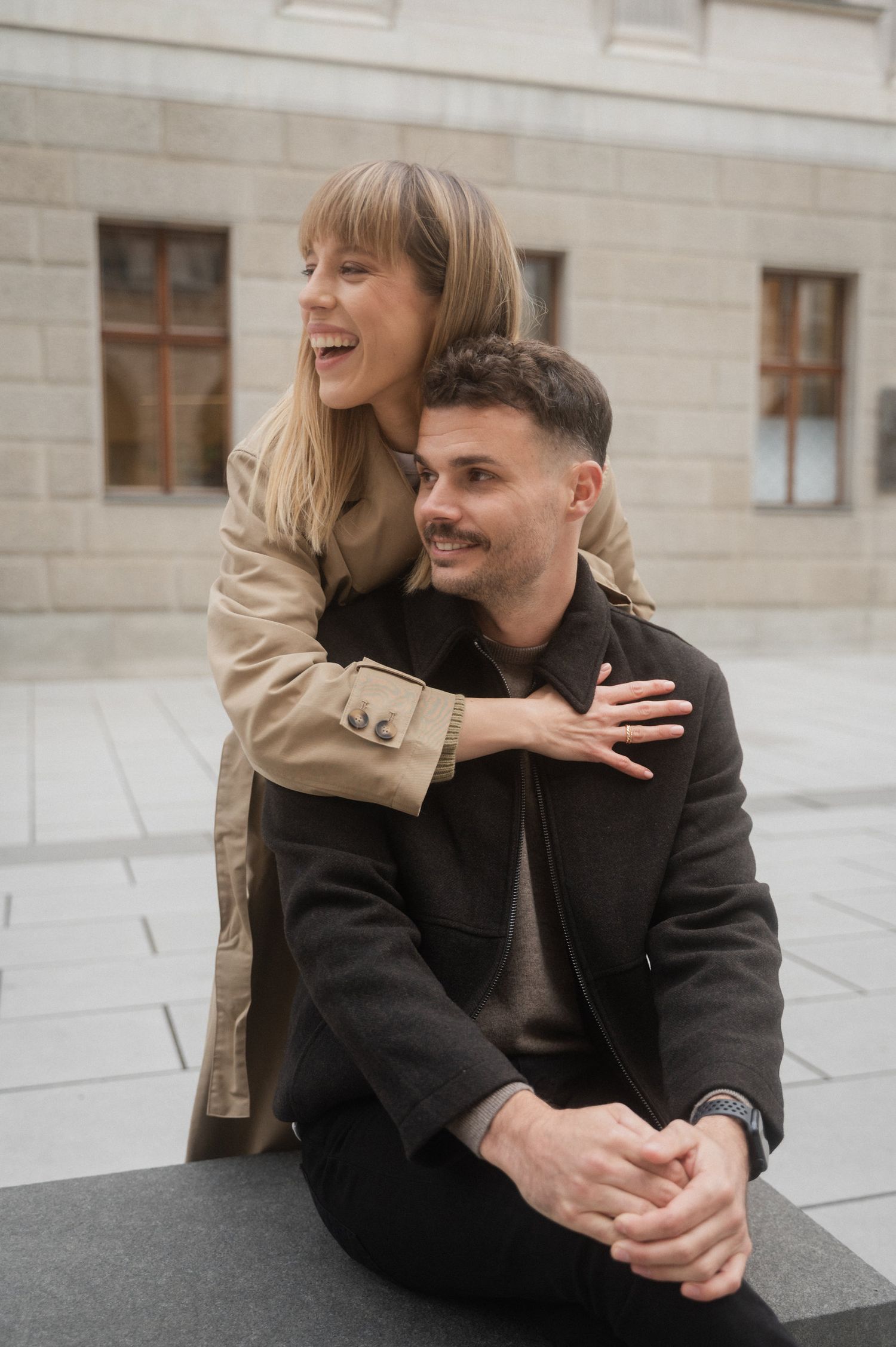 A couple shares a joyful moment together while sitting outdoors, displaying genuine laughter and affection.