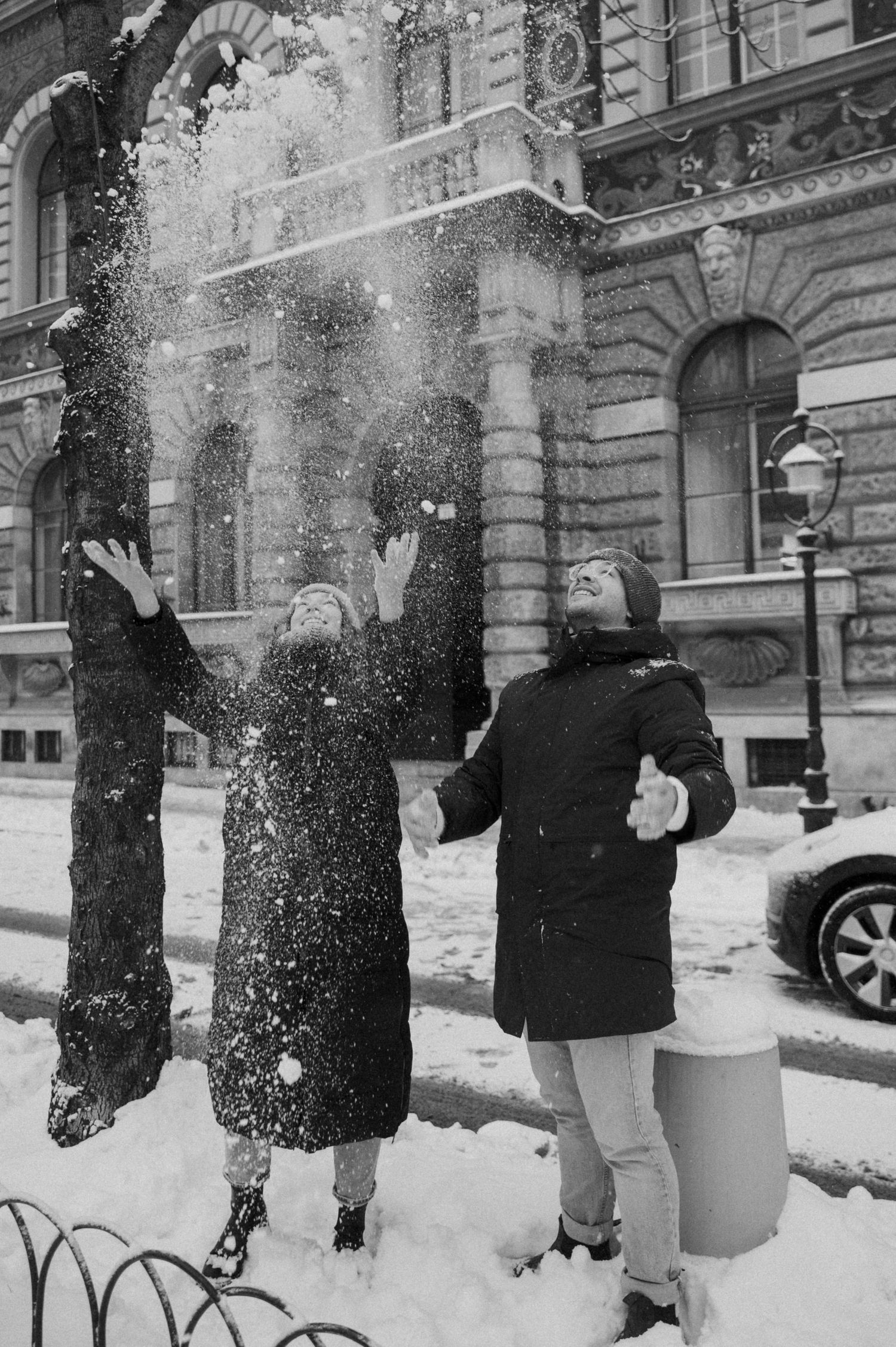 People enjoying a snowy day outside a classical stone building.