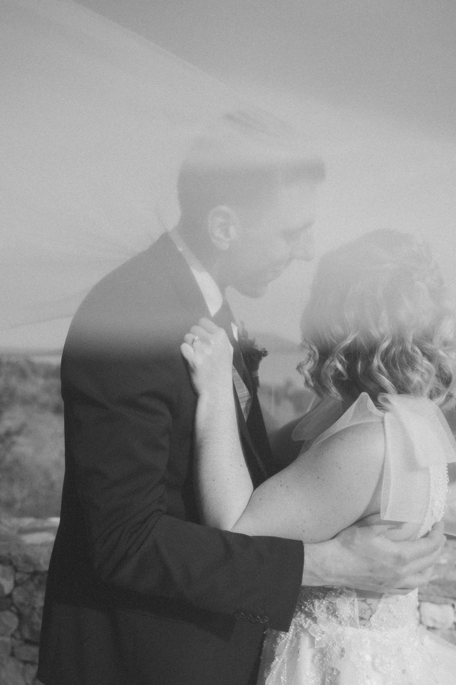 A dreamy black and white romantic moment captured in soft focus against a natural backdrop.