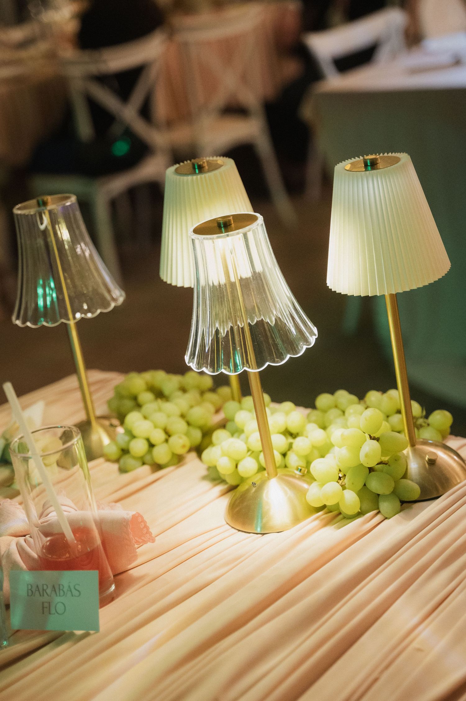 Elegant gold table lamps with pleated shades illuminate a decorative display of green grapes.