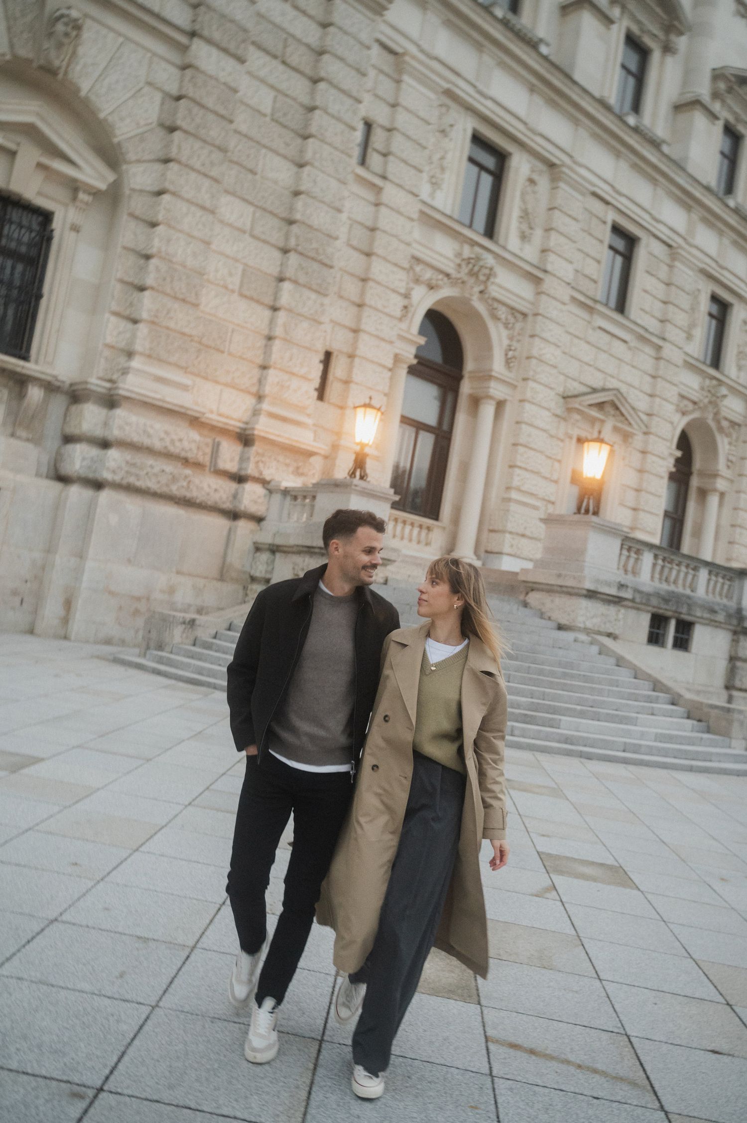 Couple walking and talking together outside a grand historic building with stone columns and stairs.