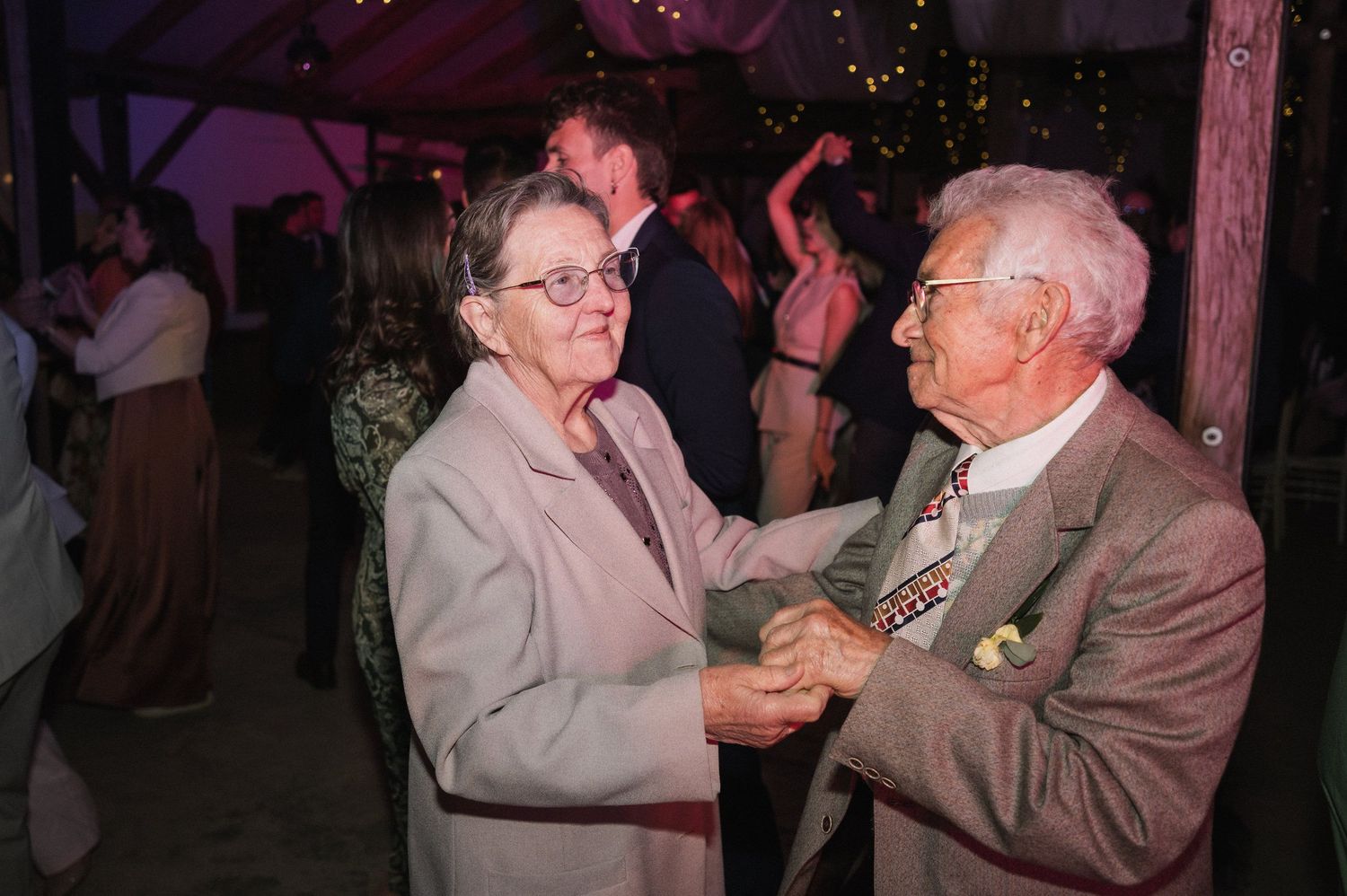 People dancing together at an evening celebration event with dim lighting and festive atmosphere.