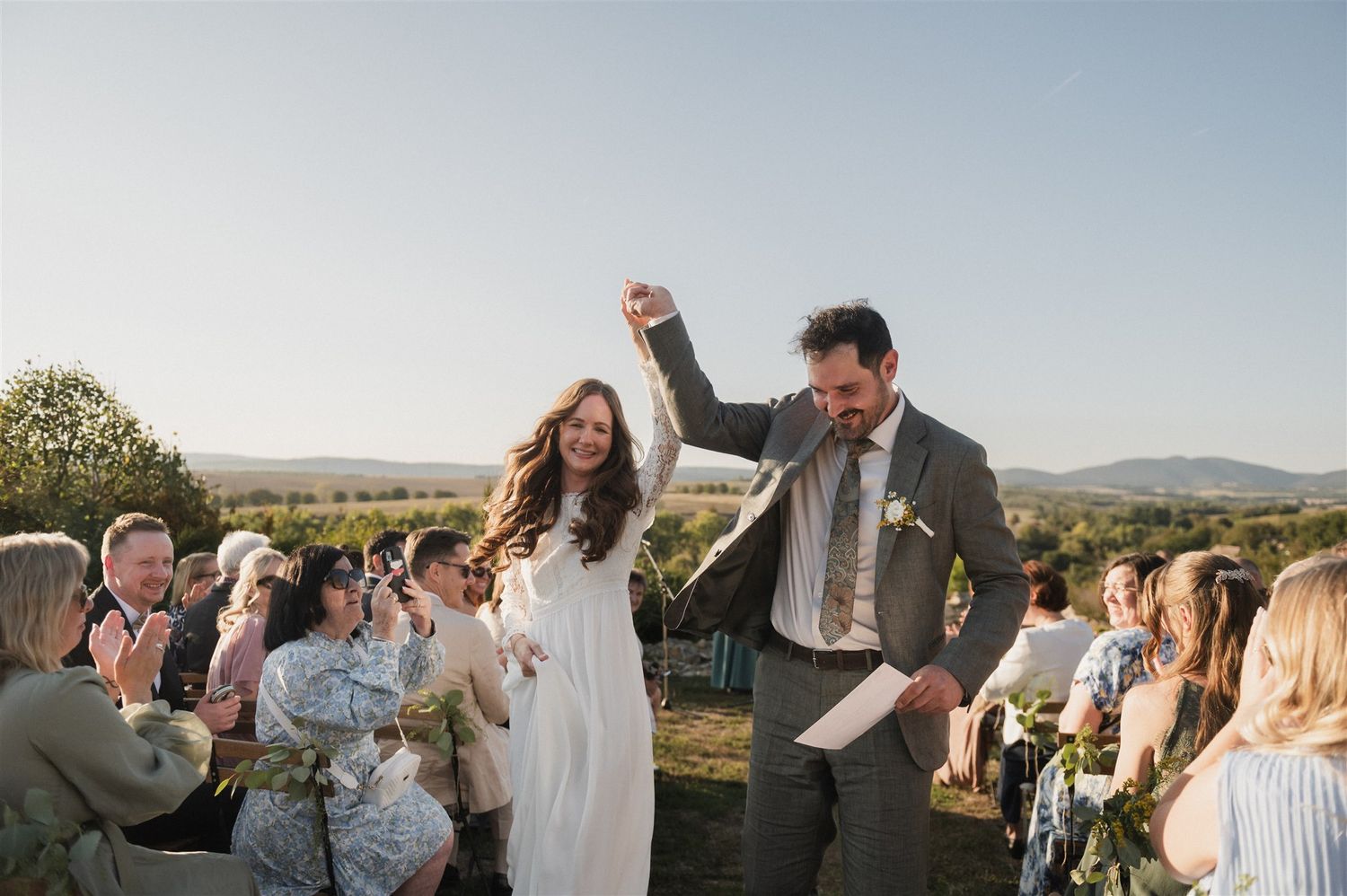 Outdoor wedding ceremony with guests celebrating under clear blue skies.