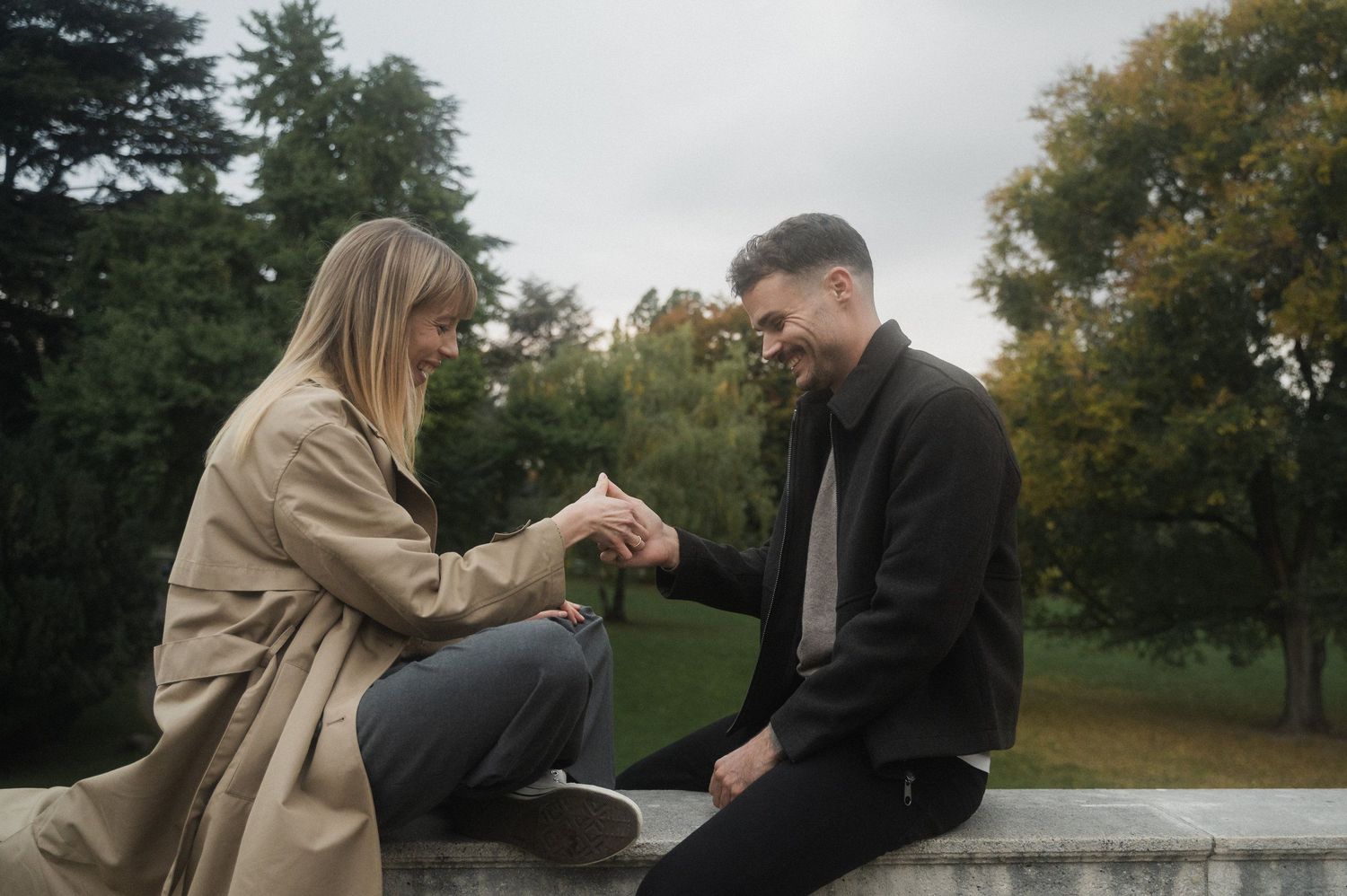 A couple sits together on a park bench in autumn, sharing an intimate conversation in the afternoon light.