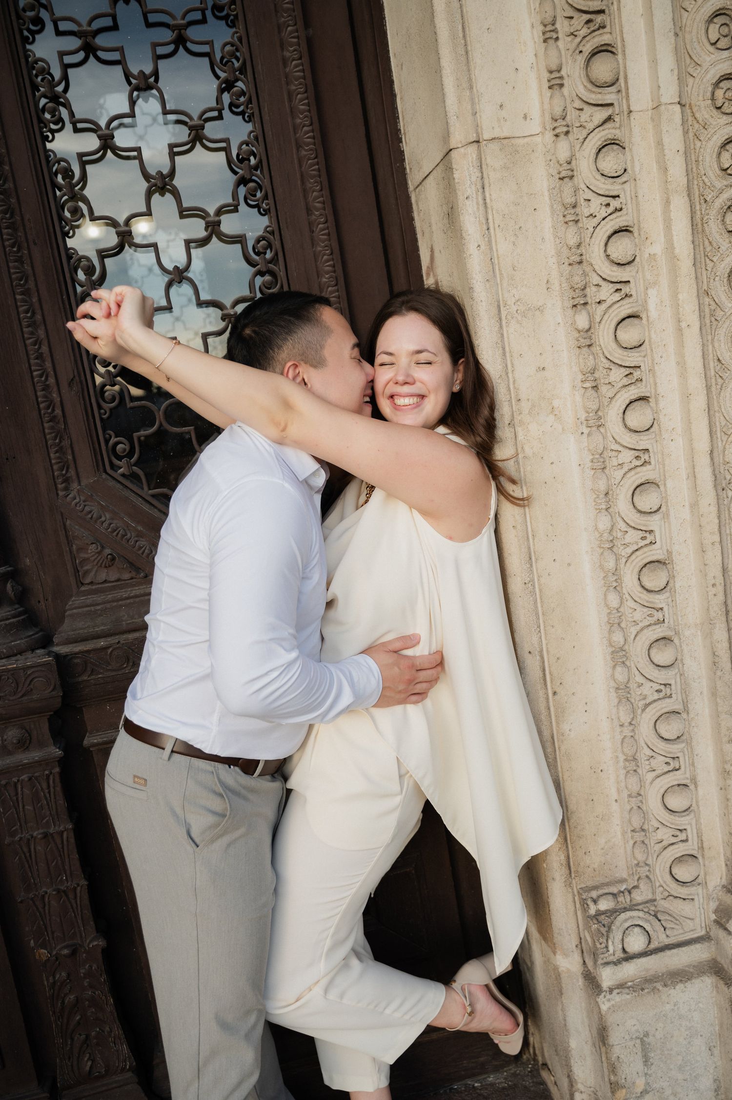 A playful couple sharing an intimate moment against an ornate doorway.