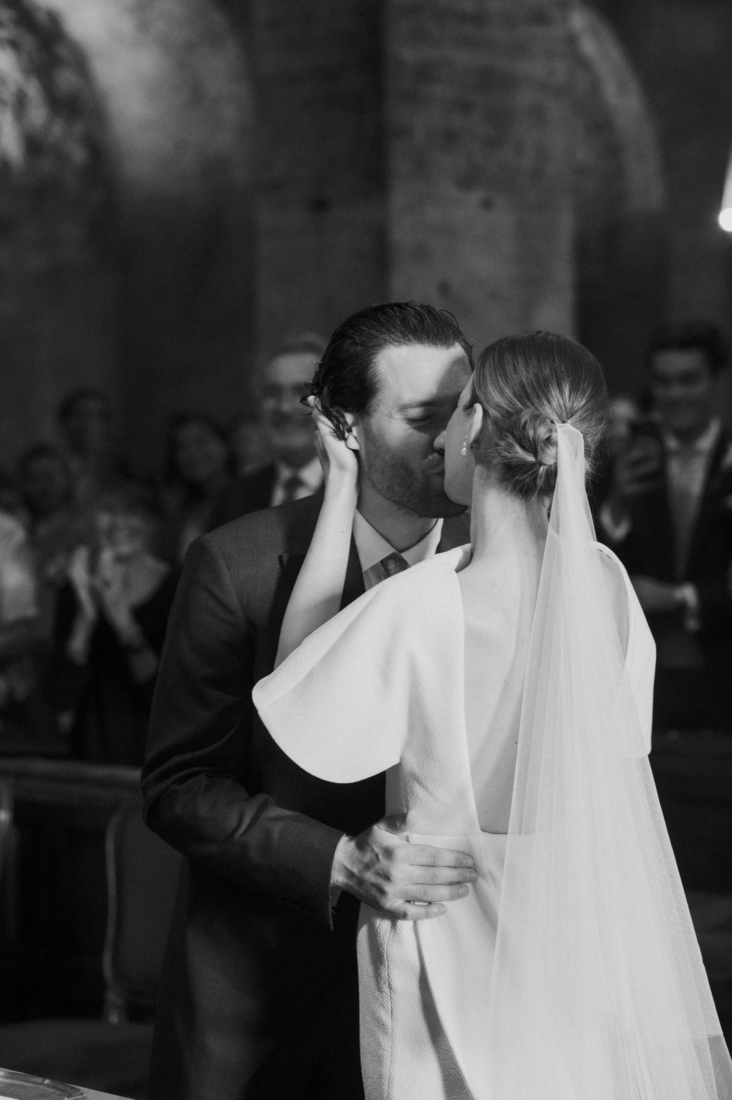 Black and white sequence of newlyweds sharing their first kiss at the altar.