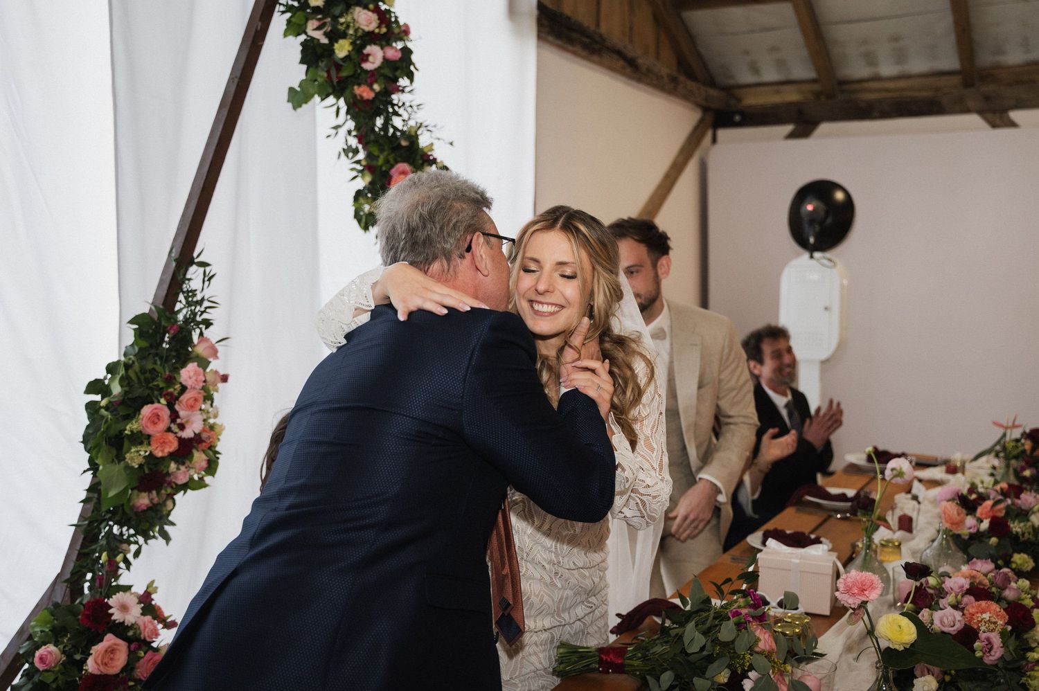 A couple shares their first dance at a wedding reception decorated with pink floral arrangements and rustic decor.