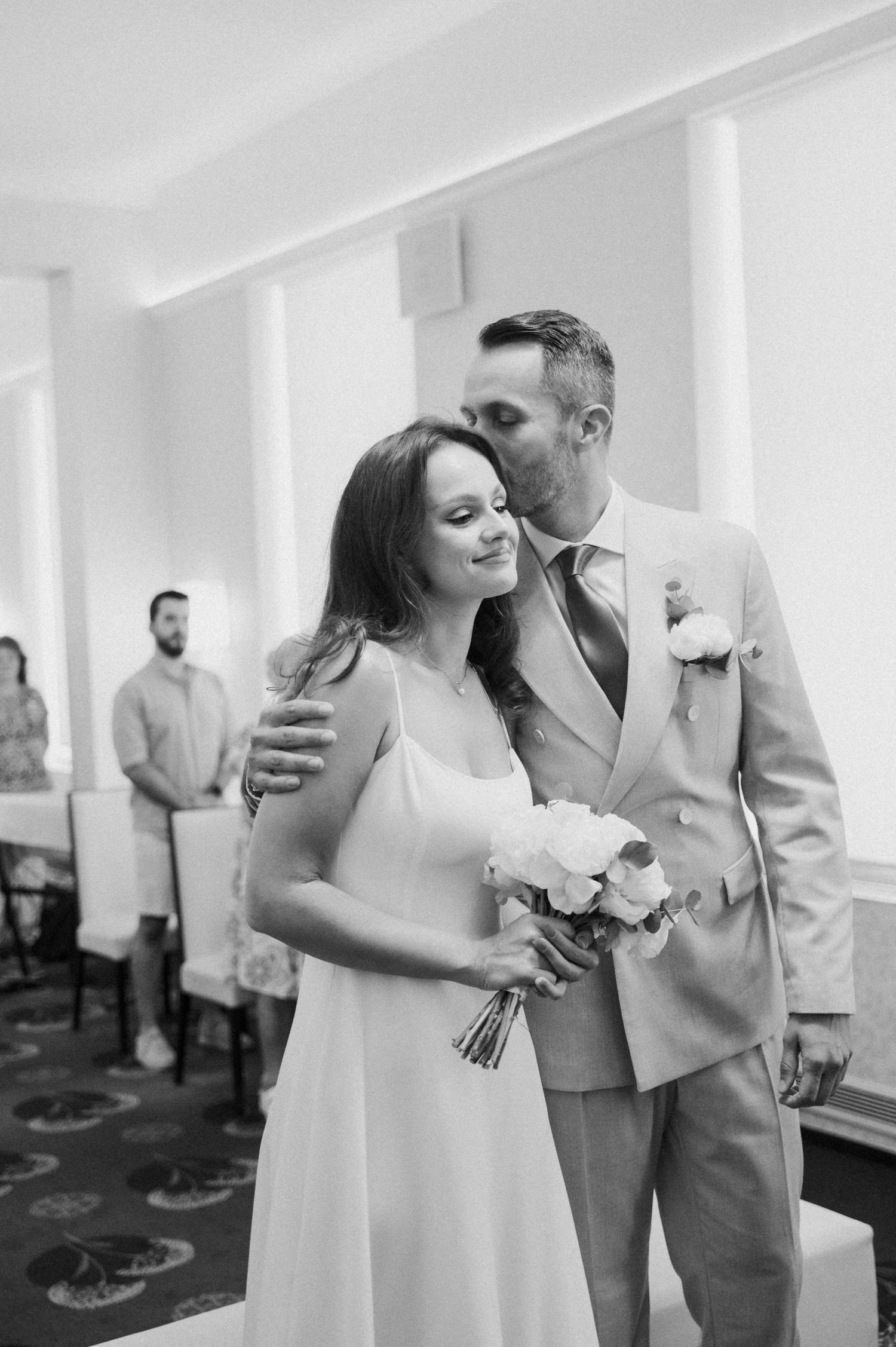 Black and white wedding photos showing tender moments between a couple in formal attire.