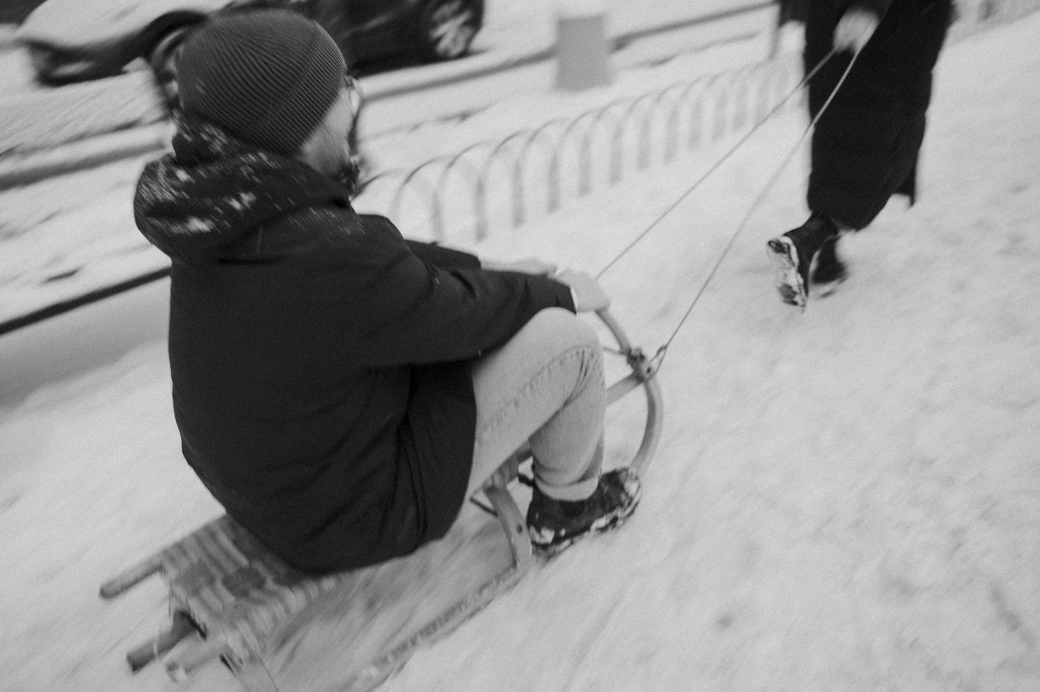 Someone riding a wooden sled down a snowy path in winter.