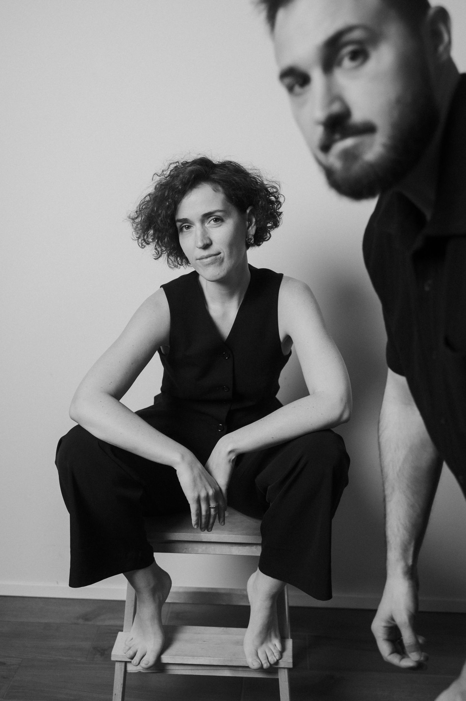 Black and white artistic portrait series showing intimate poses against a minimalist white wall background.