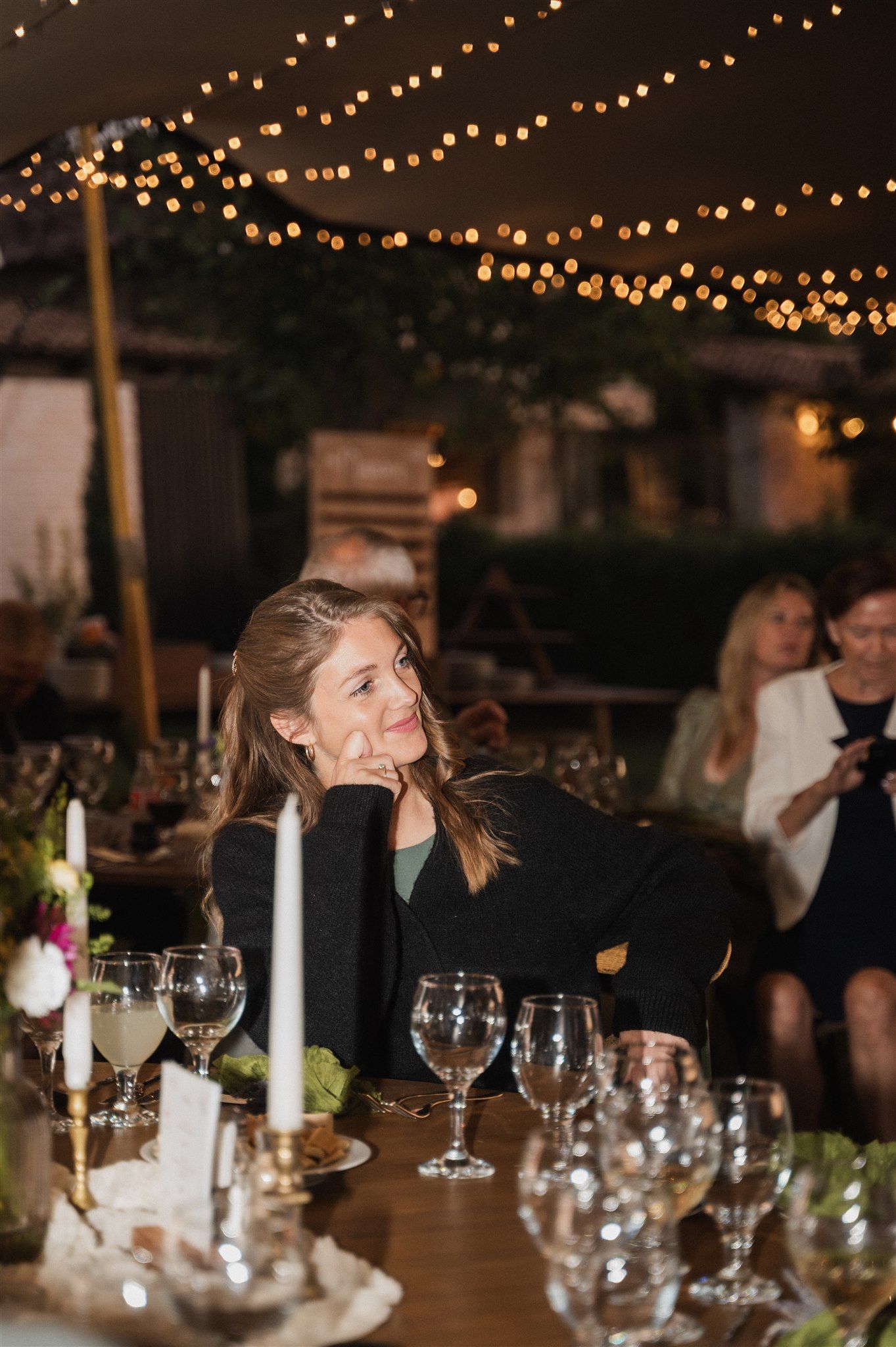 Evening wedding reception with string lights and elegant table settings creating warm ambiance.