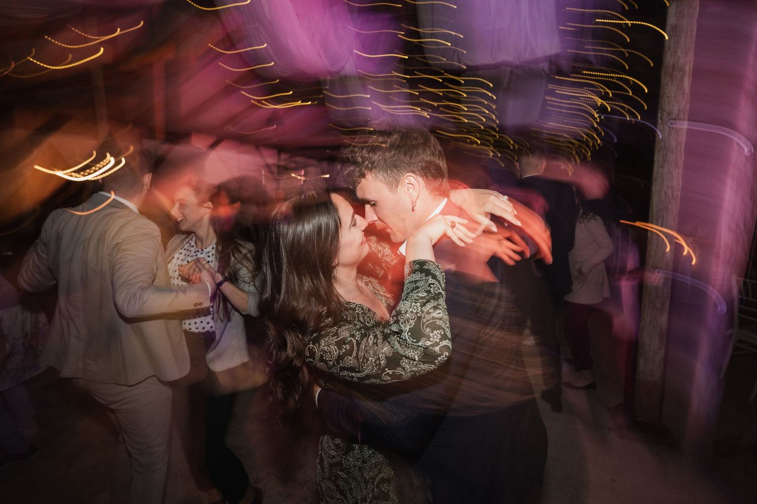 Blurred motion shots of dancers moving on a dance floor with purple lighting effects in the background.
