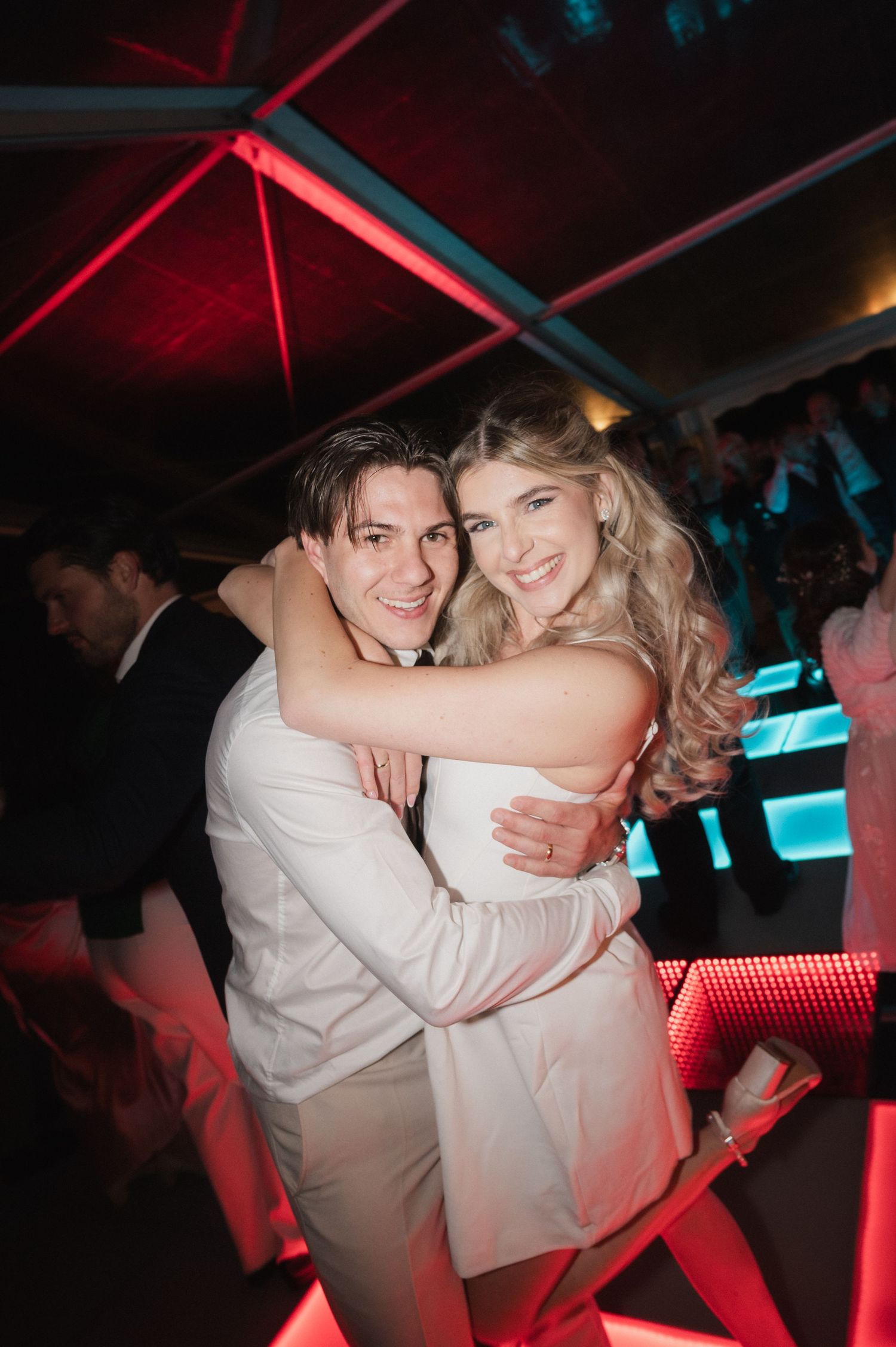 Bride and groom embracing and smiling together on the dance floor during their wedding reception.