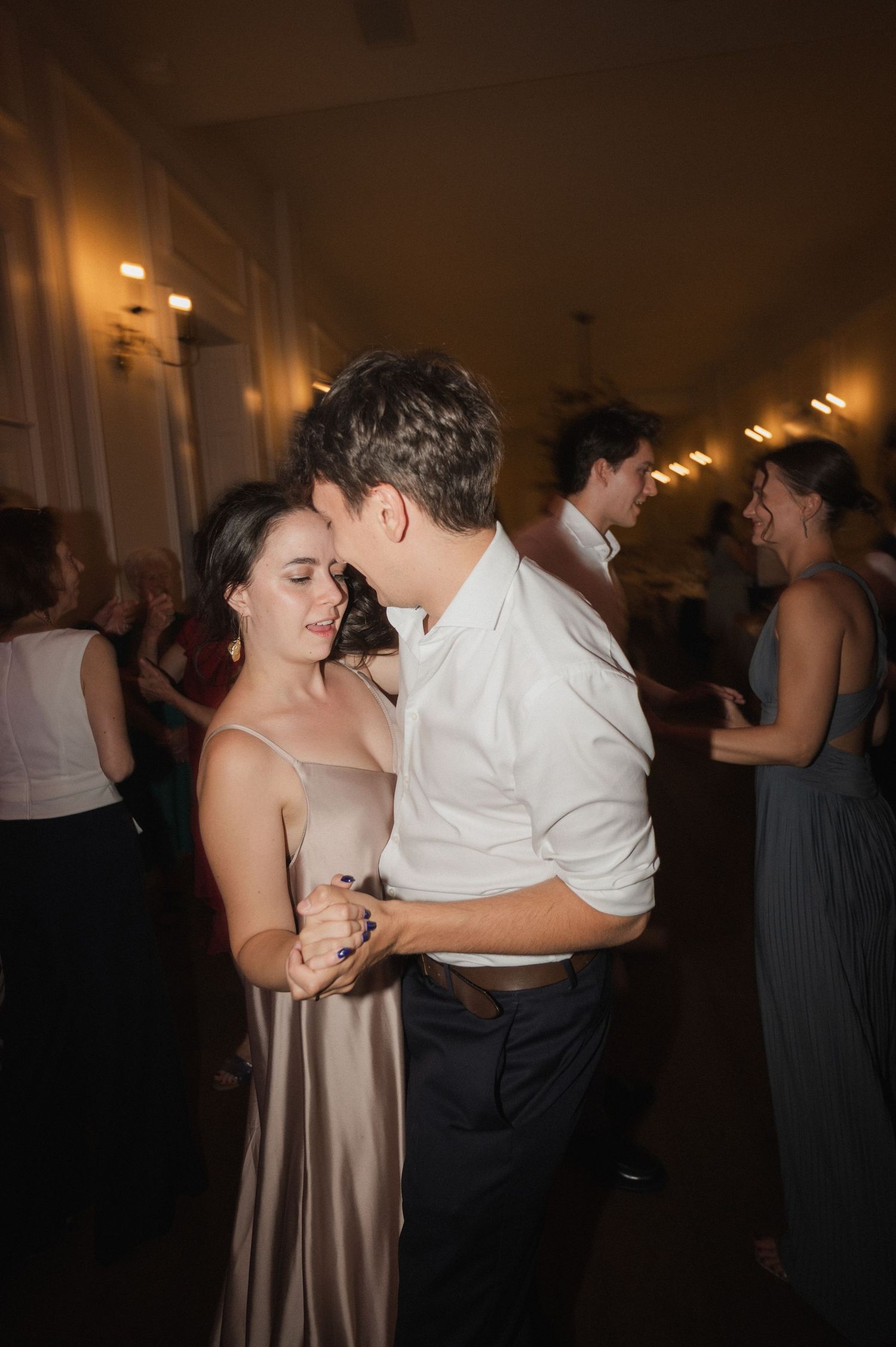 Couple sharing an intimate slow dance together at a warmly lit elegant wedding reception.