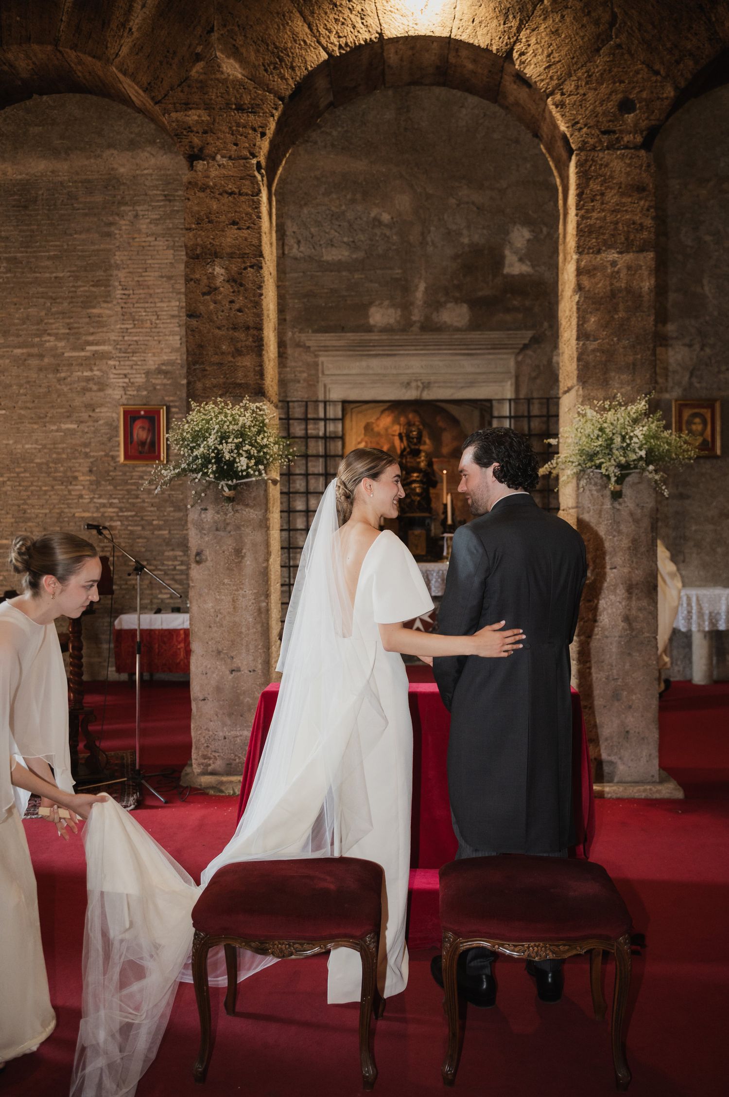 Wedding ceremony in a historic brick venue with arched architecture and red carpet.
