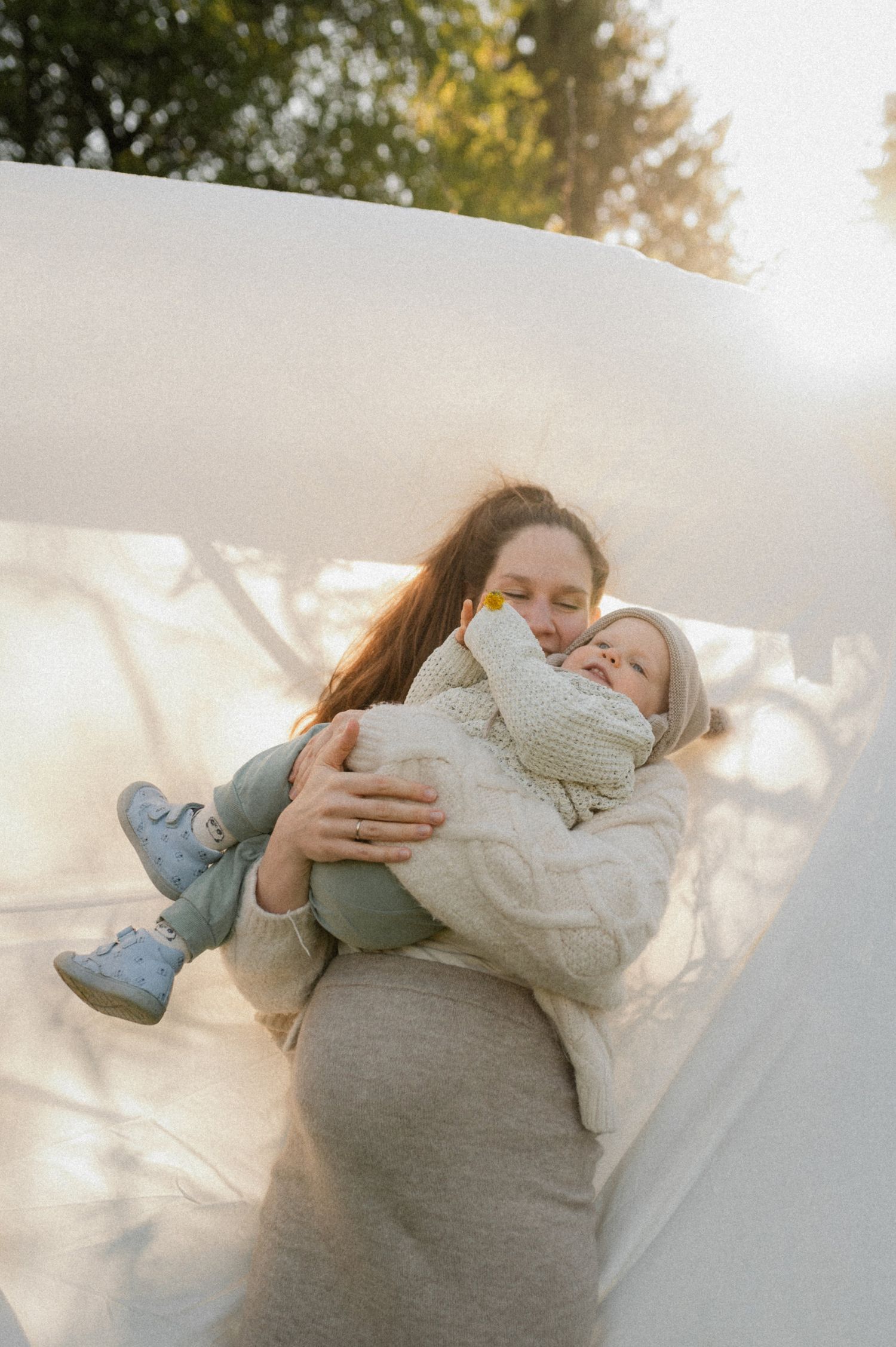 A series of candid outdoor photos showing tender moments between parent and child in soft natural lighting.