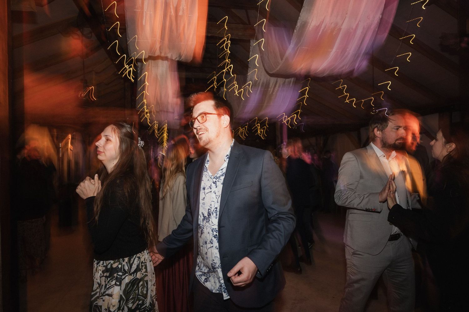 Wedding guests enjoying themselves on a dimly lit dance floor during an evening celebration.