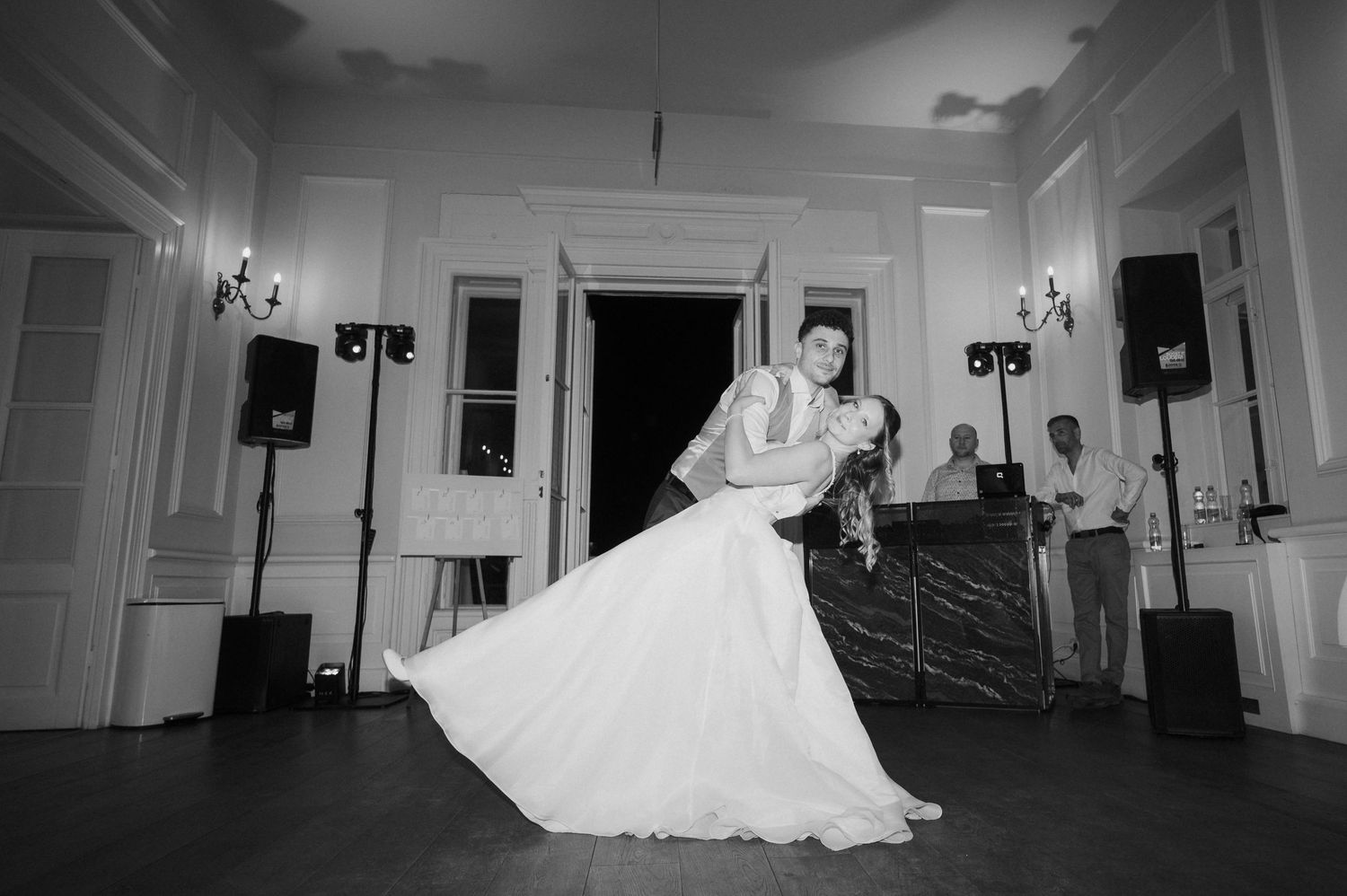 Bride and groom sharing romantic first dance dip in black and white wedding reception photo.