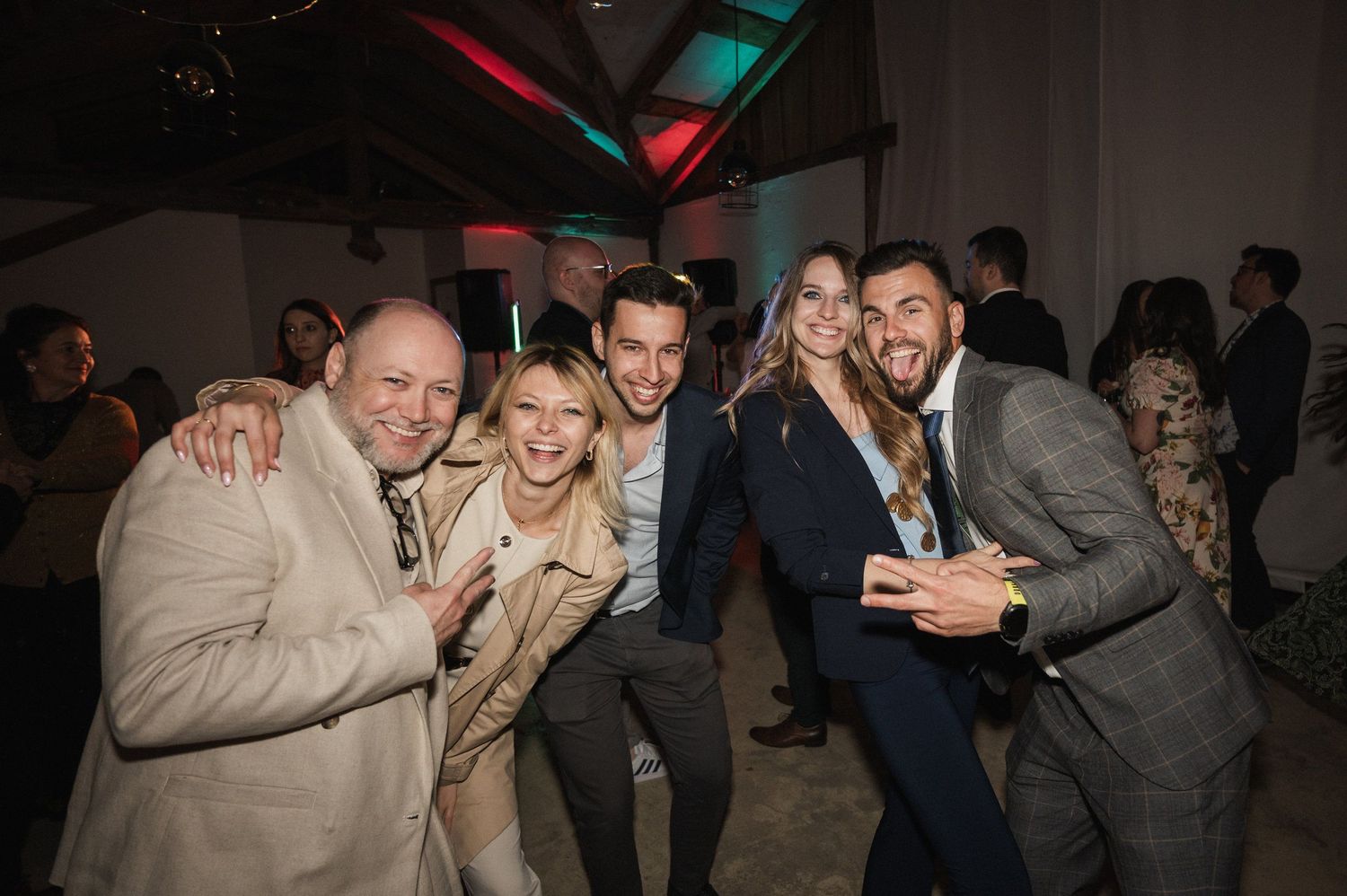 Party guests enjoying themselves at a dimly lit indoor event with colorful ambient lighting.