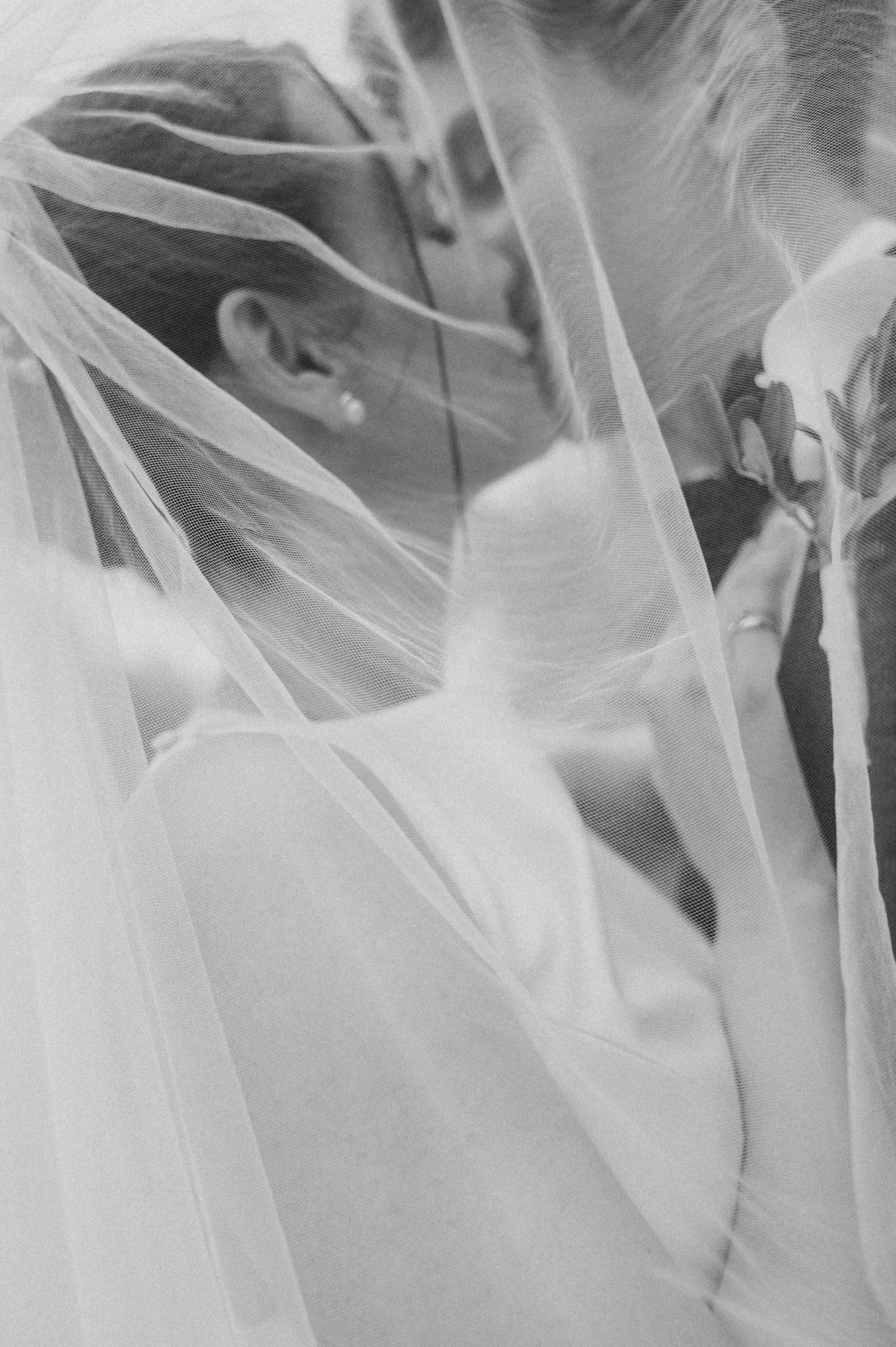 Ethereal close-up shots of delicate white wedding veil details in black and white.