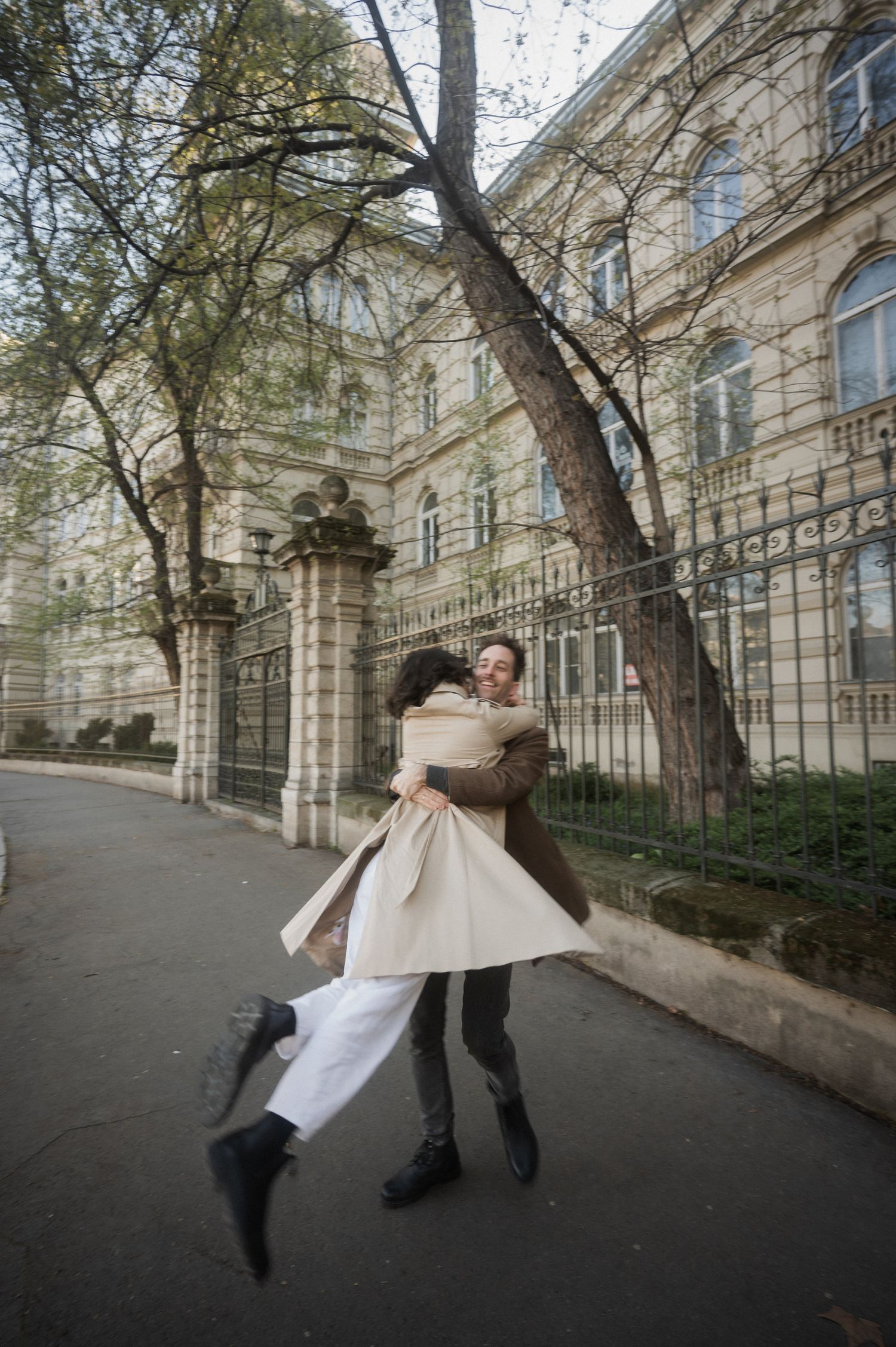 A sequence of motion shots showing a person in a white coat spinning and twirling on a tree-lined urban street.
