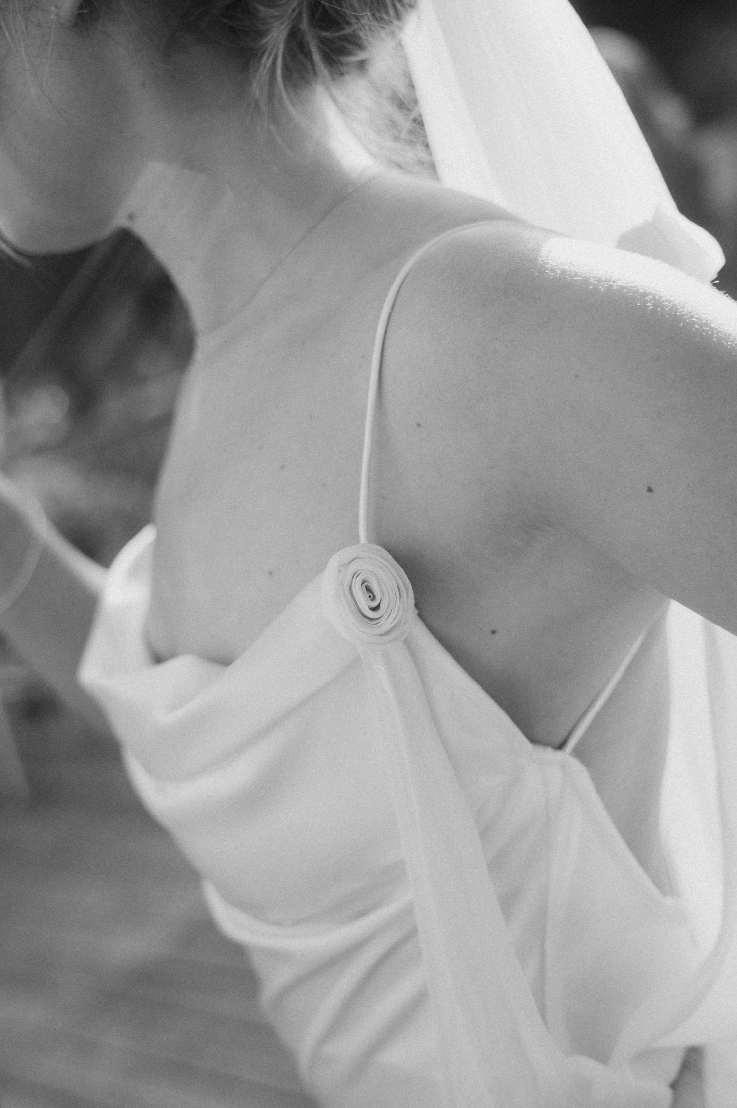 Close-up of bride's backless wedding dress with delicate spaghetti straps and rose detail.