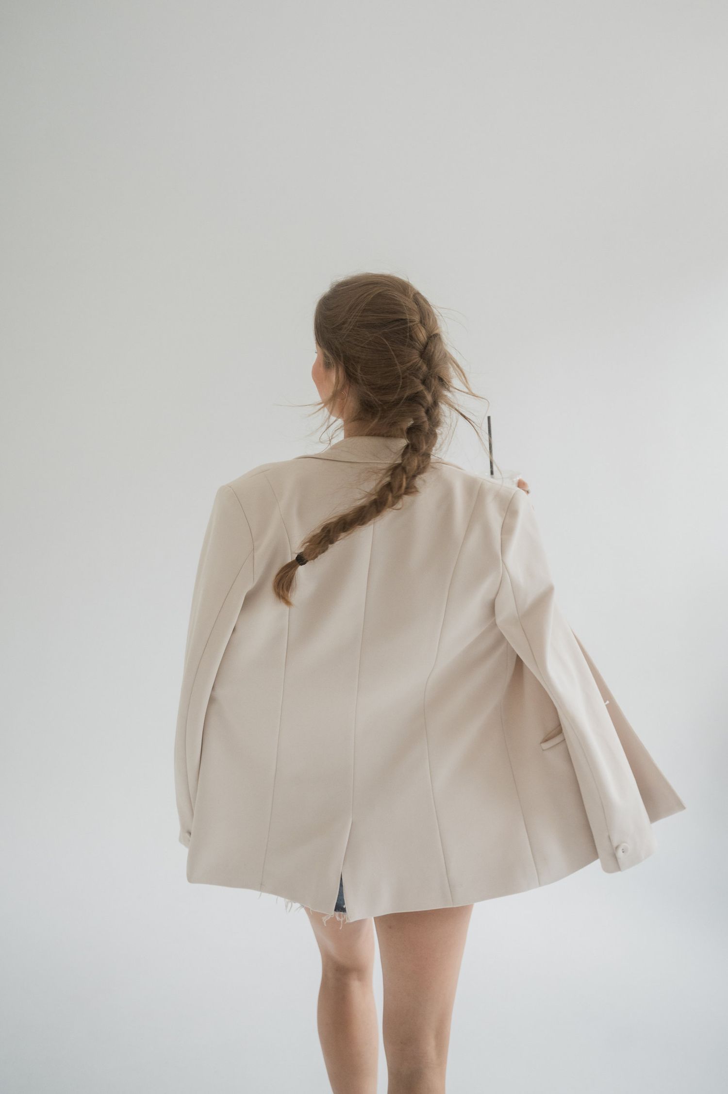 Artistic fashion portrait series showing a model in a cream colored blazer against a white background.