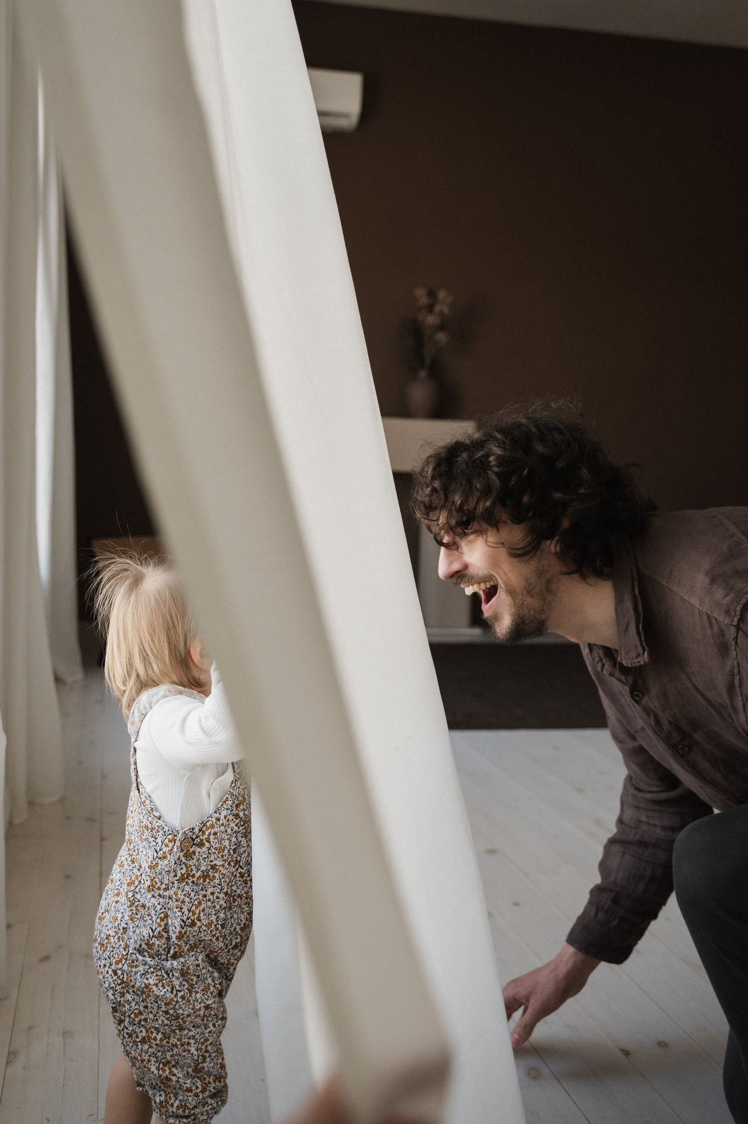 Two people interacting playfully in a minimalist interior with diagonal architectural elements.