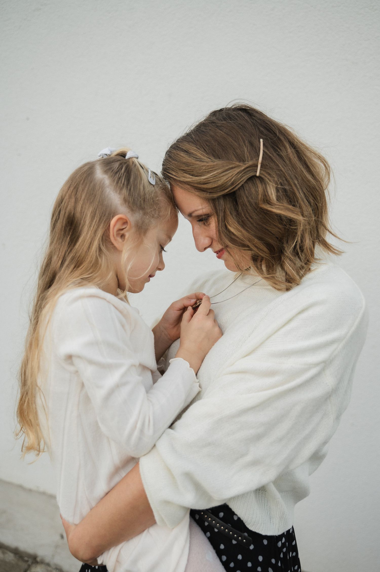 Two people in white shirts lean towards each other in an intimate moment against a light background.