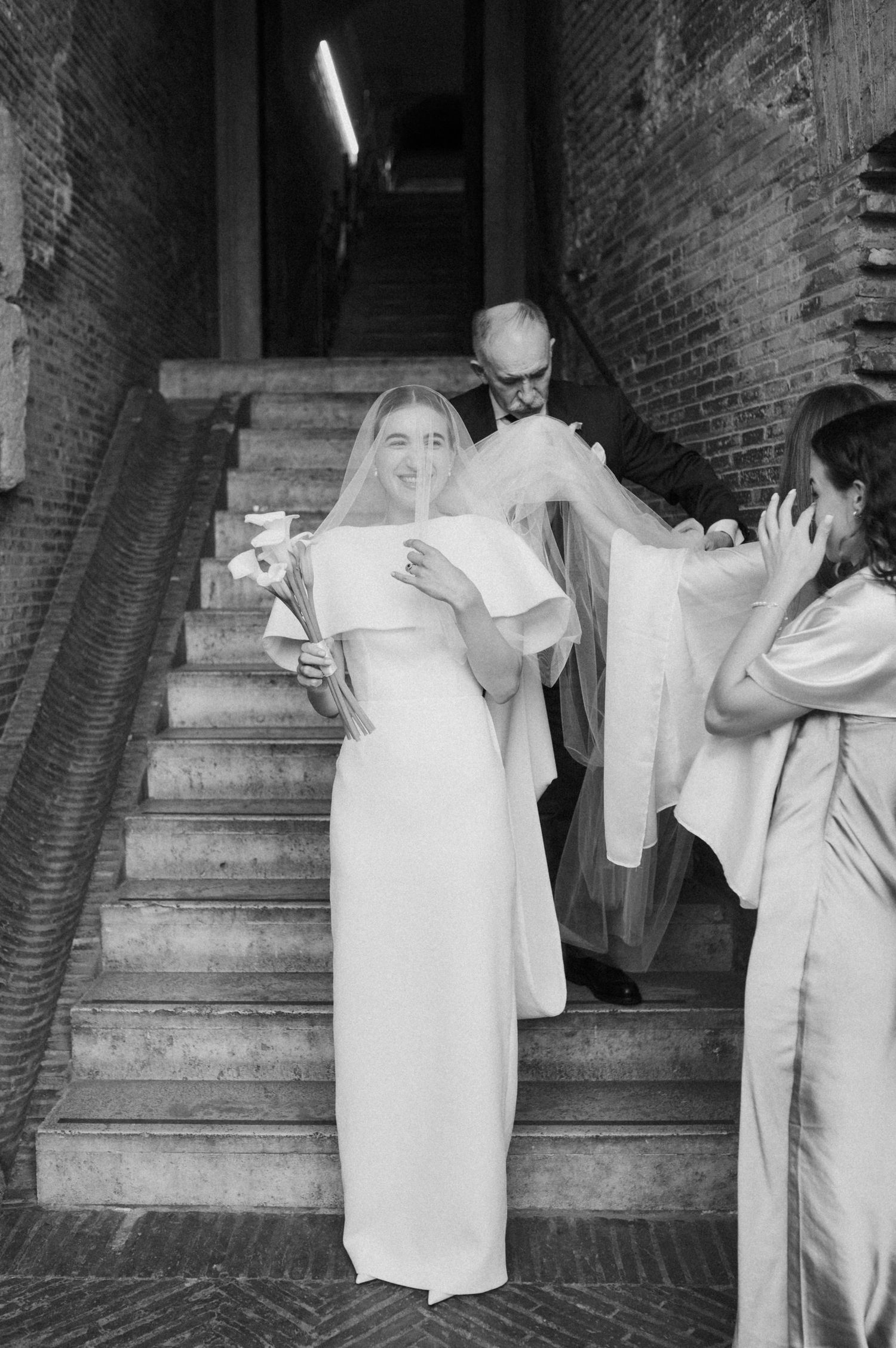 Wedding party members in formal attire interacting on stone steps.
