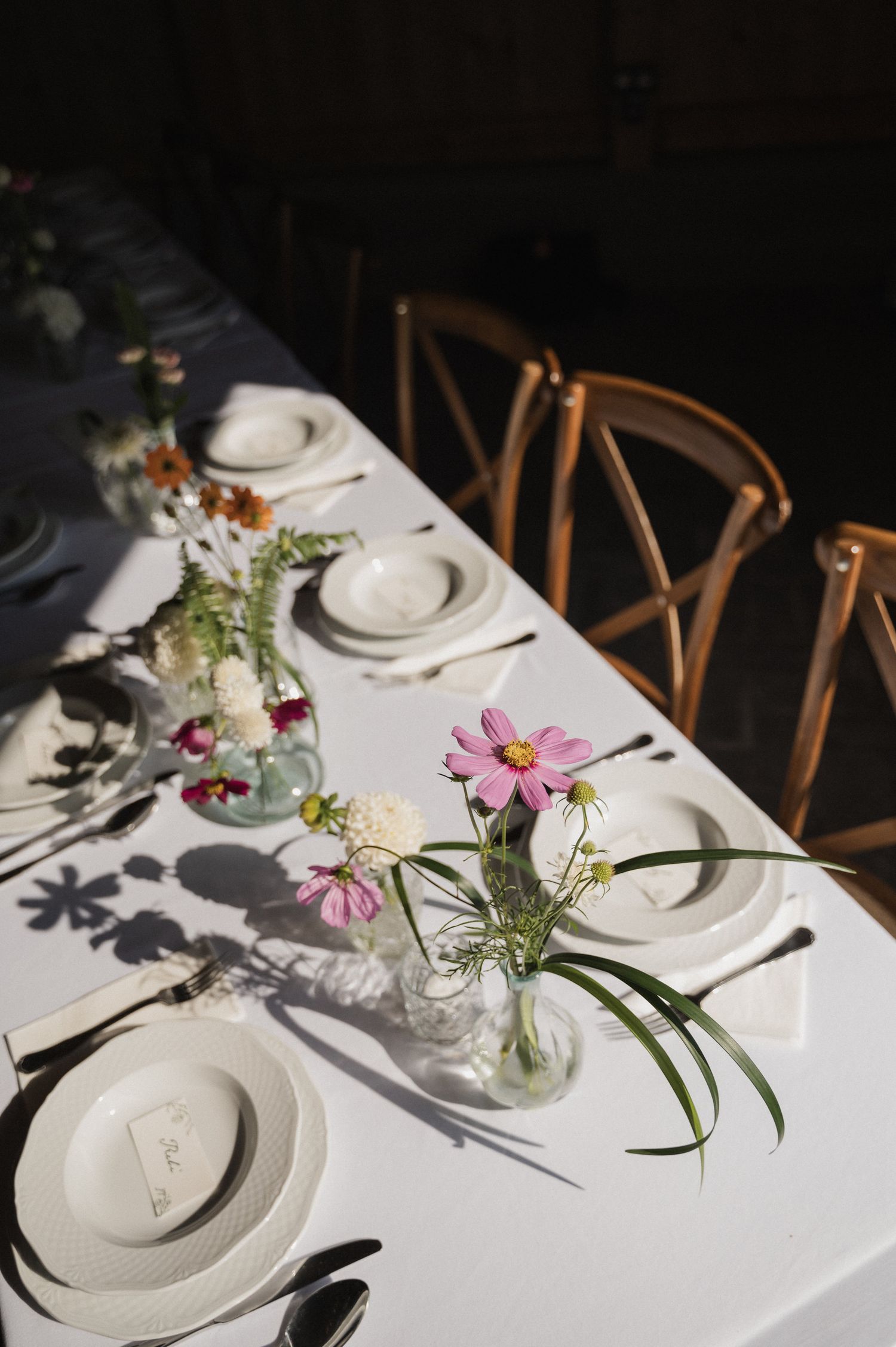 Elegant table setting with pink flowers in vases and white plates.