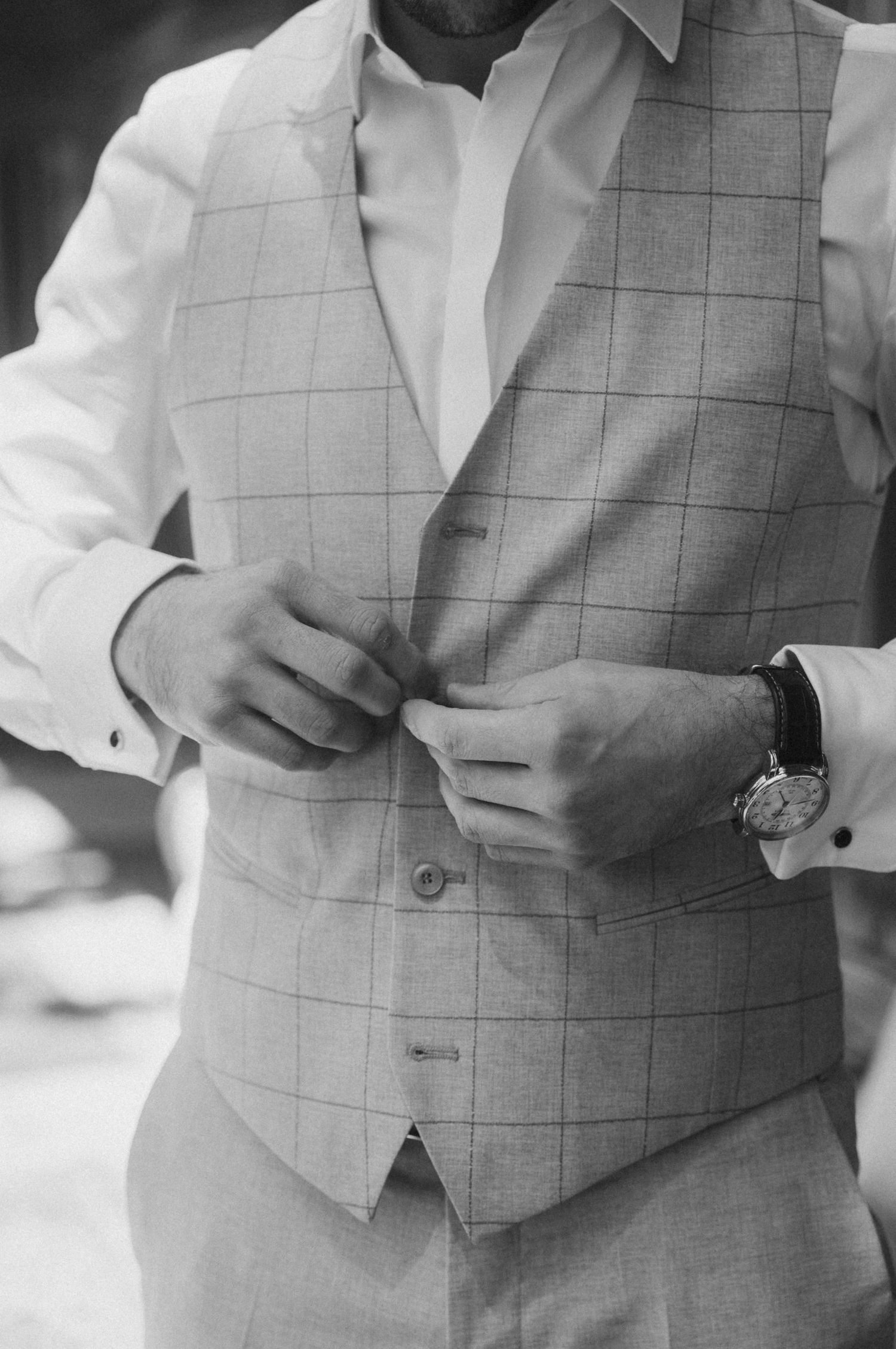 Close-up shots of a gray windowpane check vest being adjusted and buttoned.