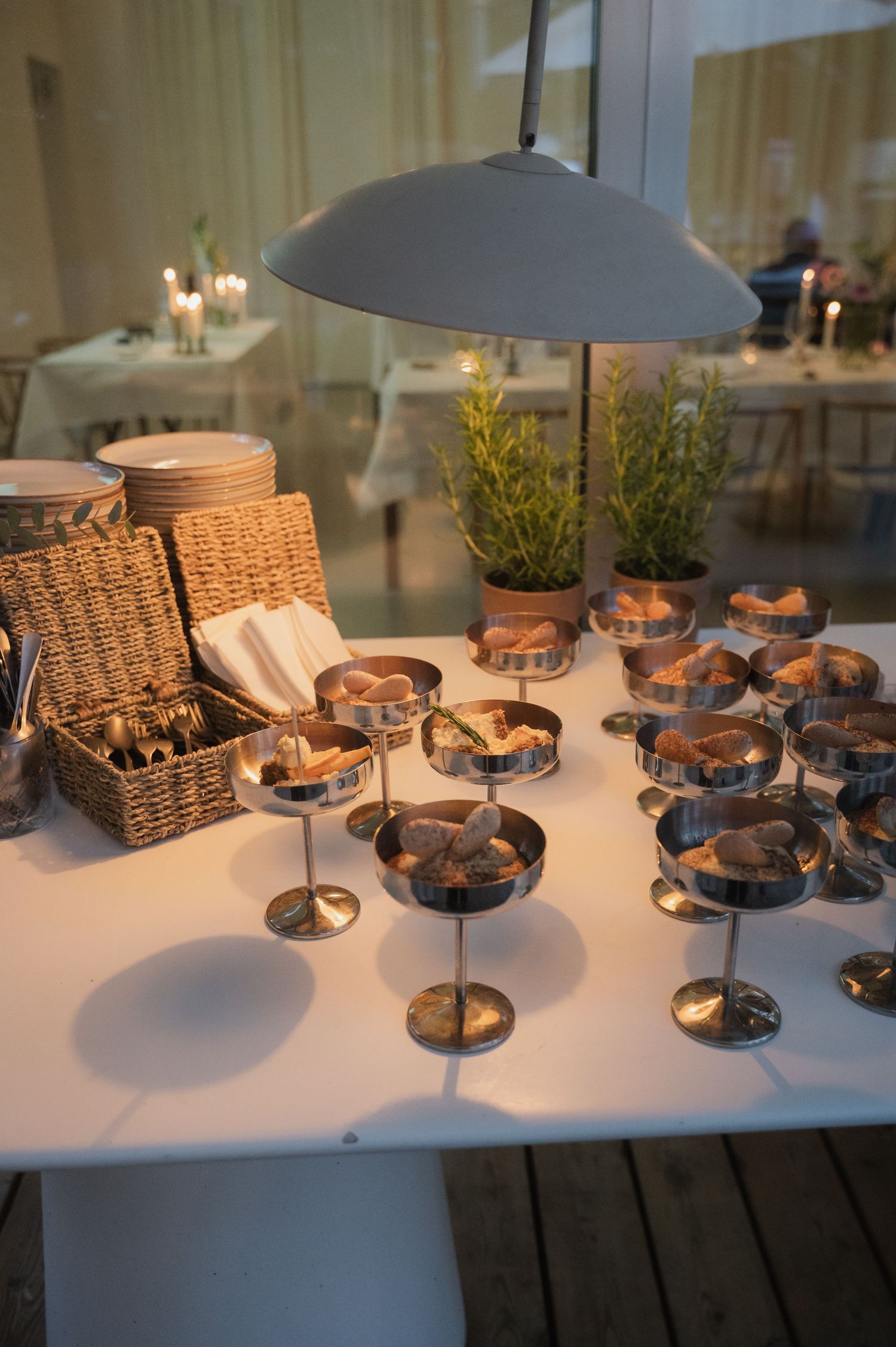 Elegant wedding reception table with silver champagne coupes and wicker basket centerpiece.