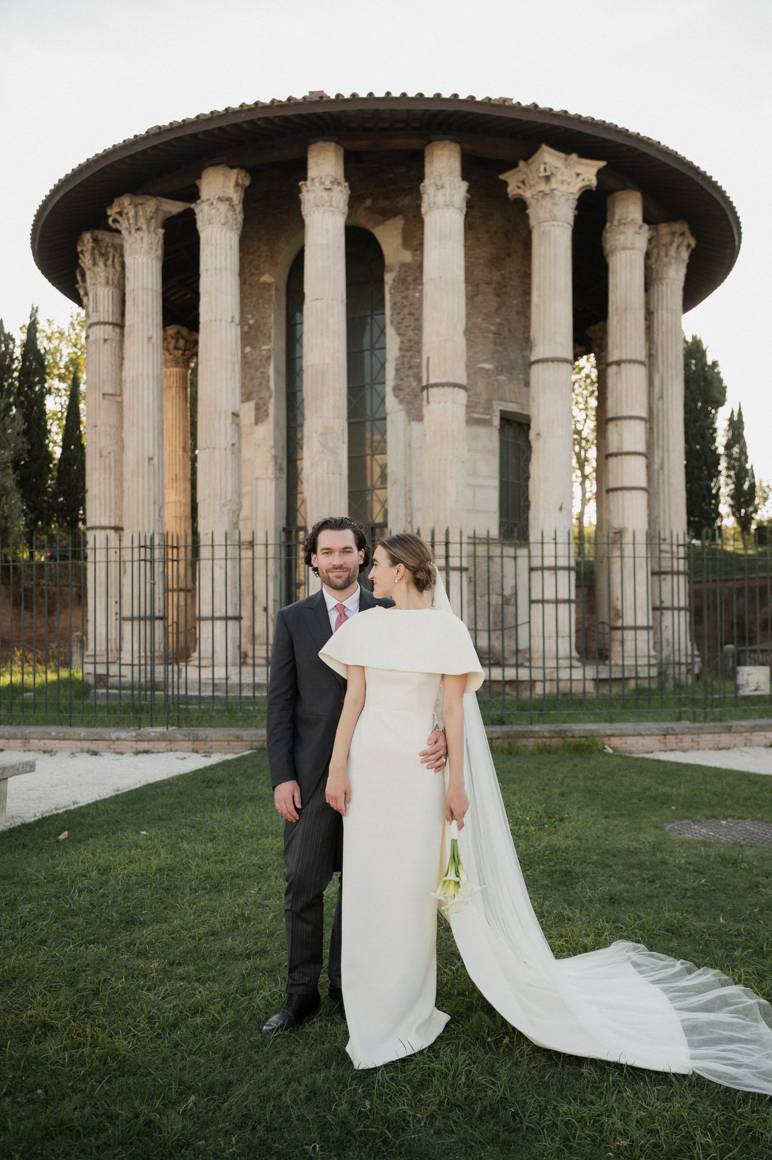 Elegant wedding portraits captured against a backdrop of ancient Roman columns and green lawn.