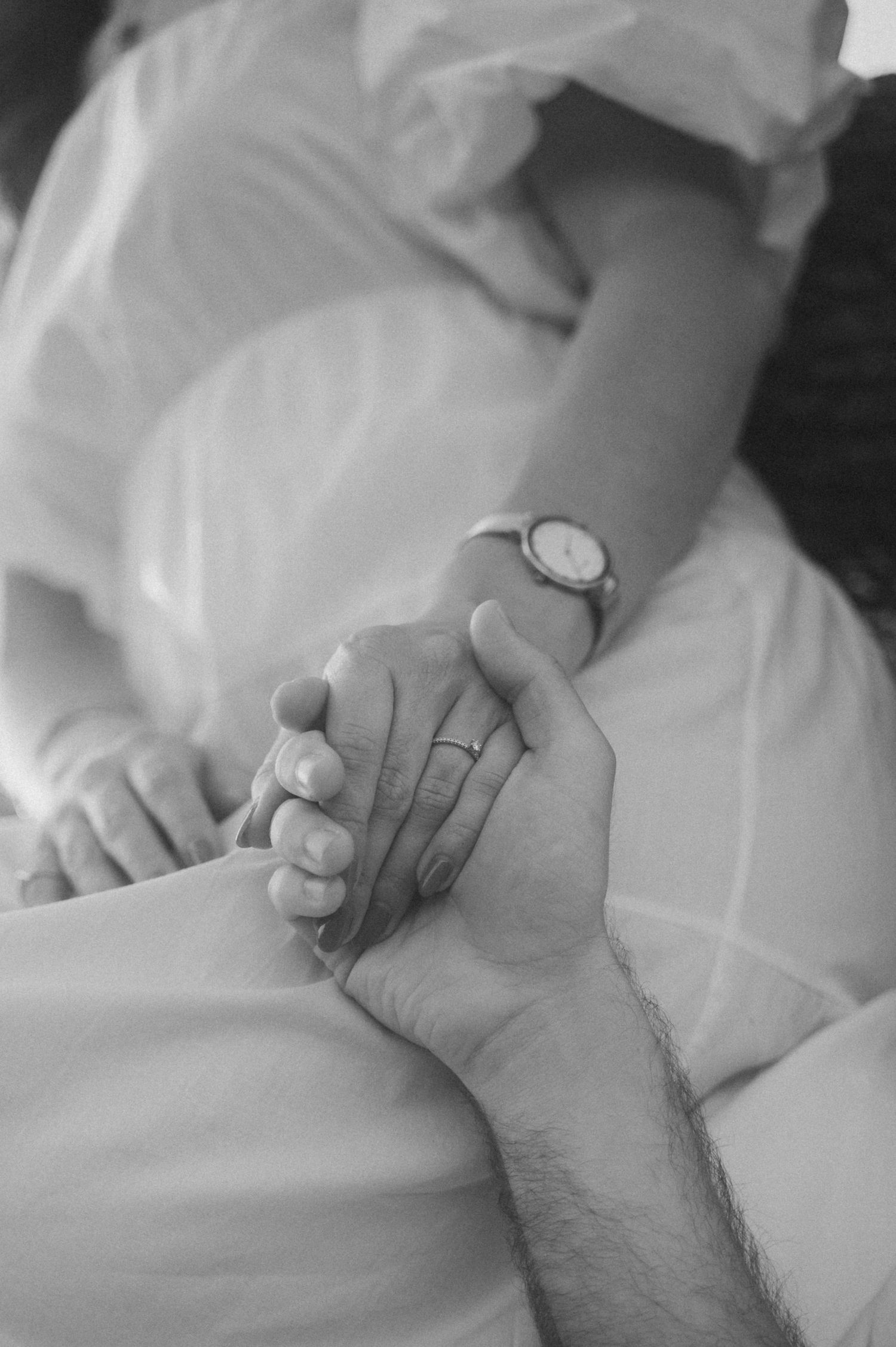 A black and white photo series showing hands gently holding each other against white bedding.