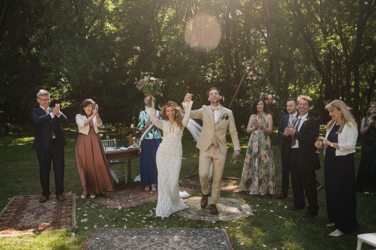 Wedding guests celebrate with bubbles in an outdoor garden setting during a summer celebration.