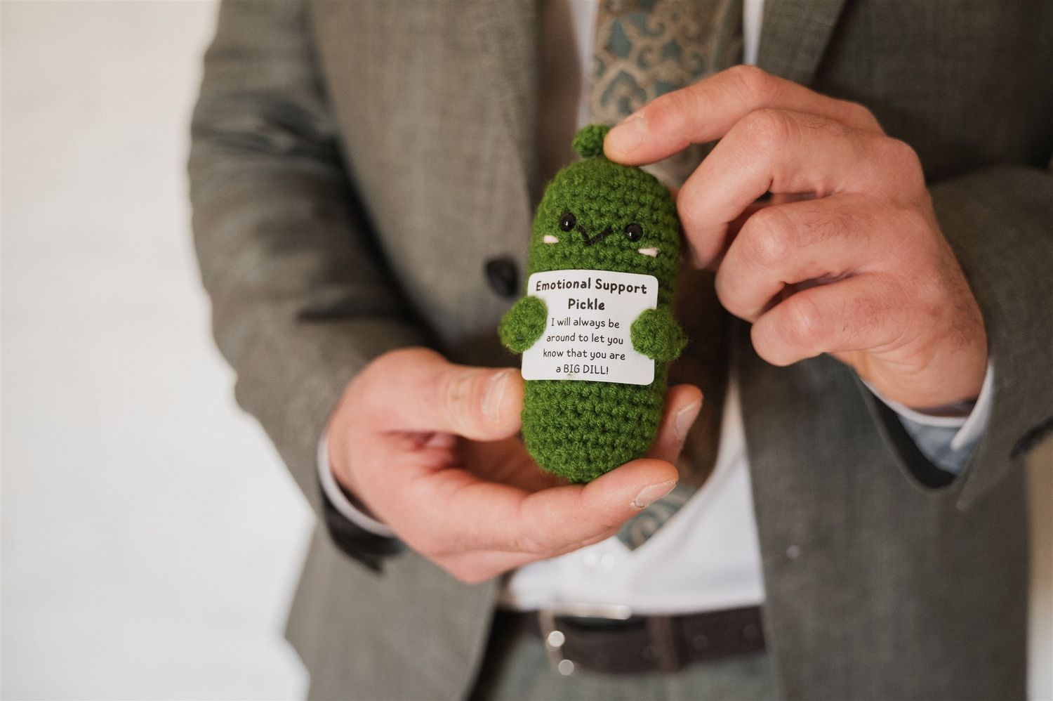Close-up of hands holding small green wedding favors or decorative items.