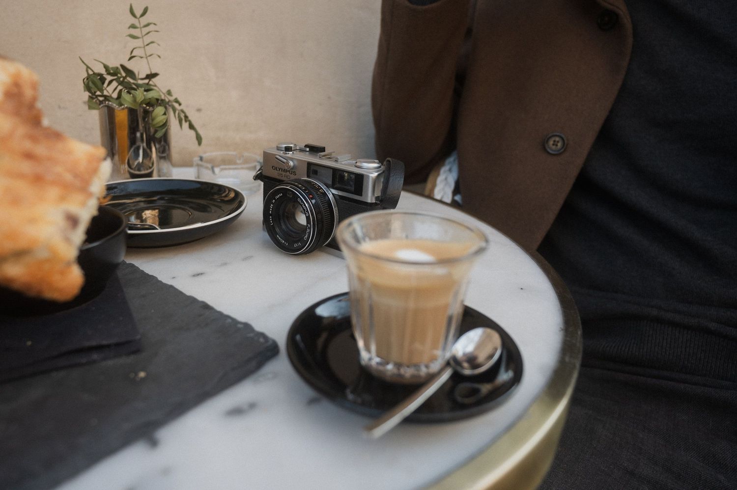 A row of coffee cups and beverages on a cafe counter, including lattes and espresso drinks.