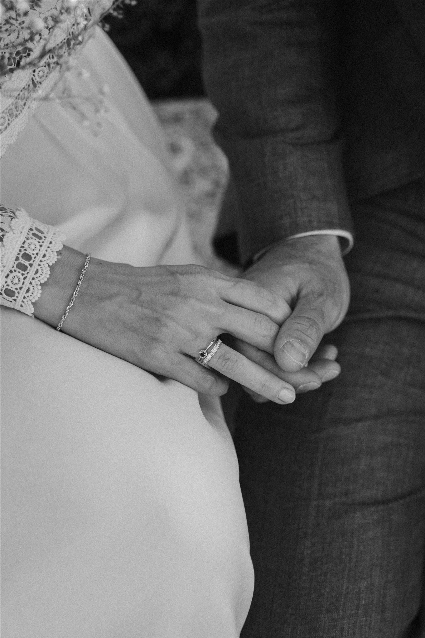 Close-up black and white shot of hands with wedding rings touching.
