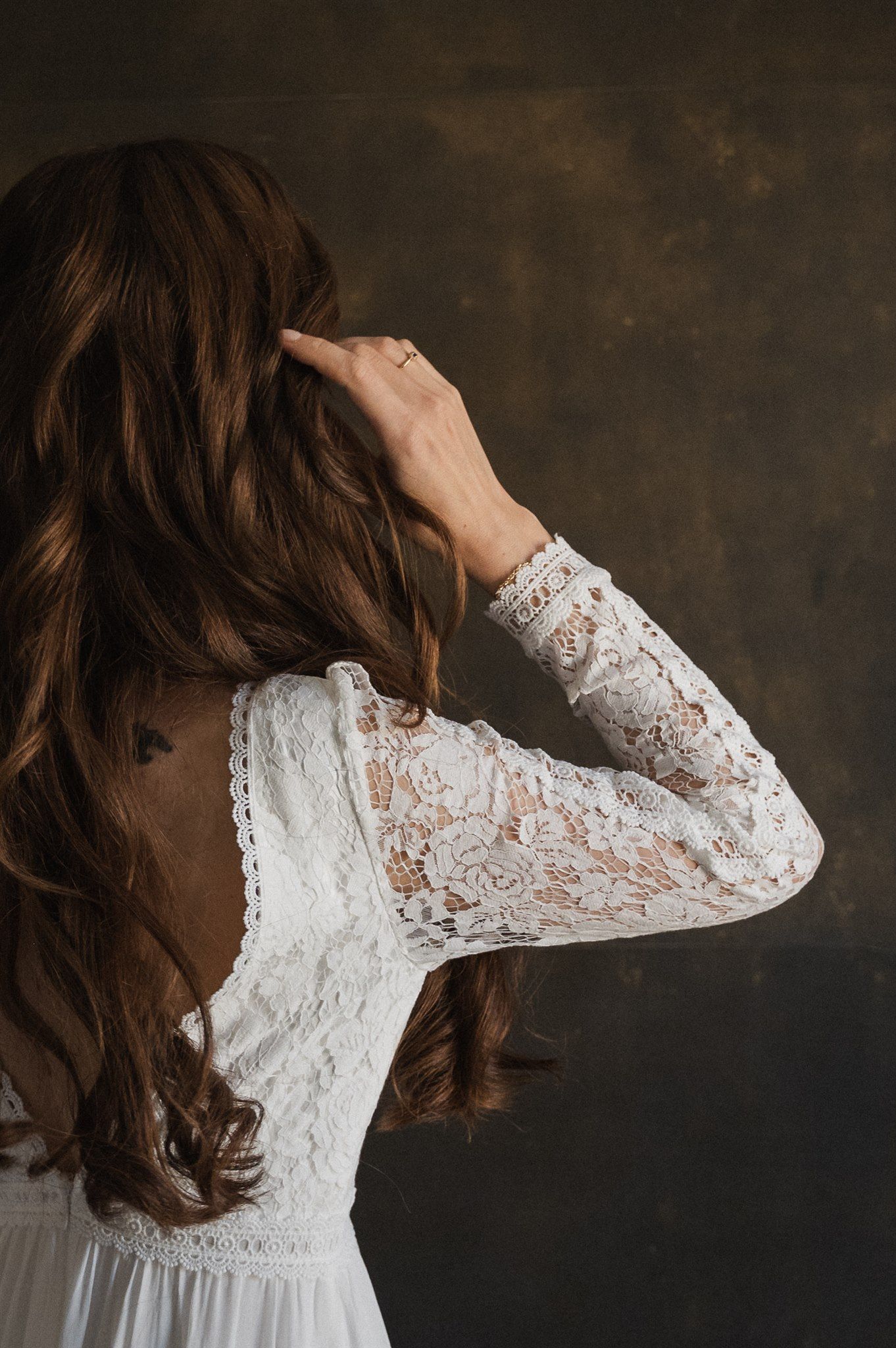 Close-up detail shots of white lace wedding dress sleeves against dark background.