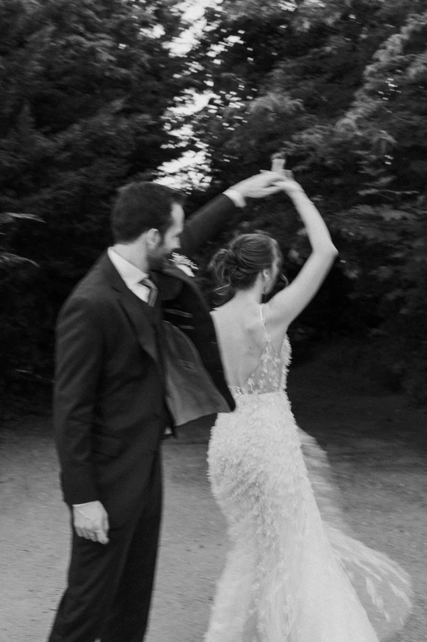 A couple in formal wedding attire dances together in a black and white photo series outdoors.